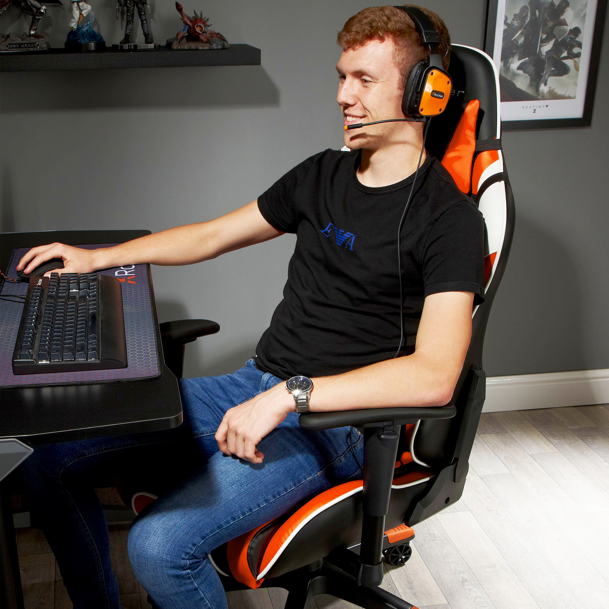 Mann sitzt in einem Gaming-Stuhl mit Kopfhörern und schaut auf den Monitor. Eine Tastatur ist davor.