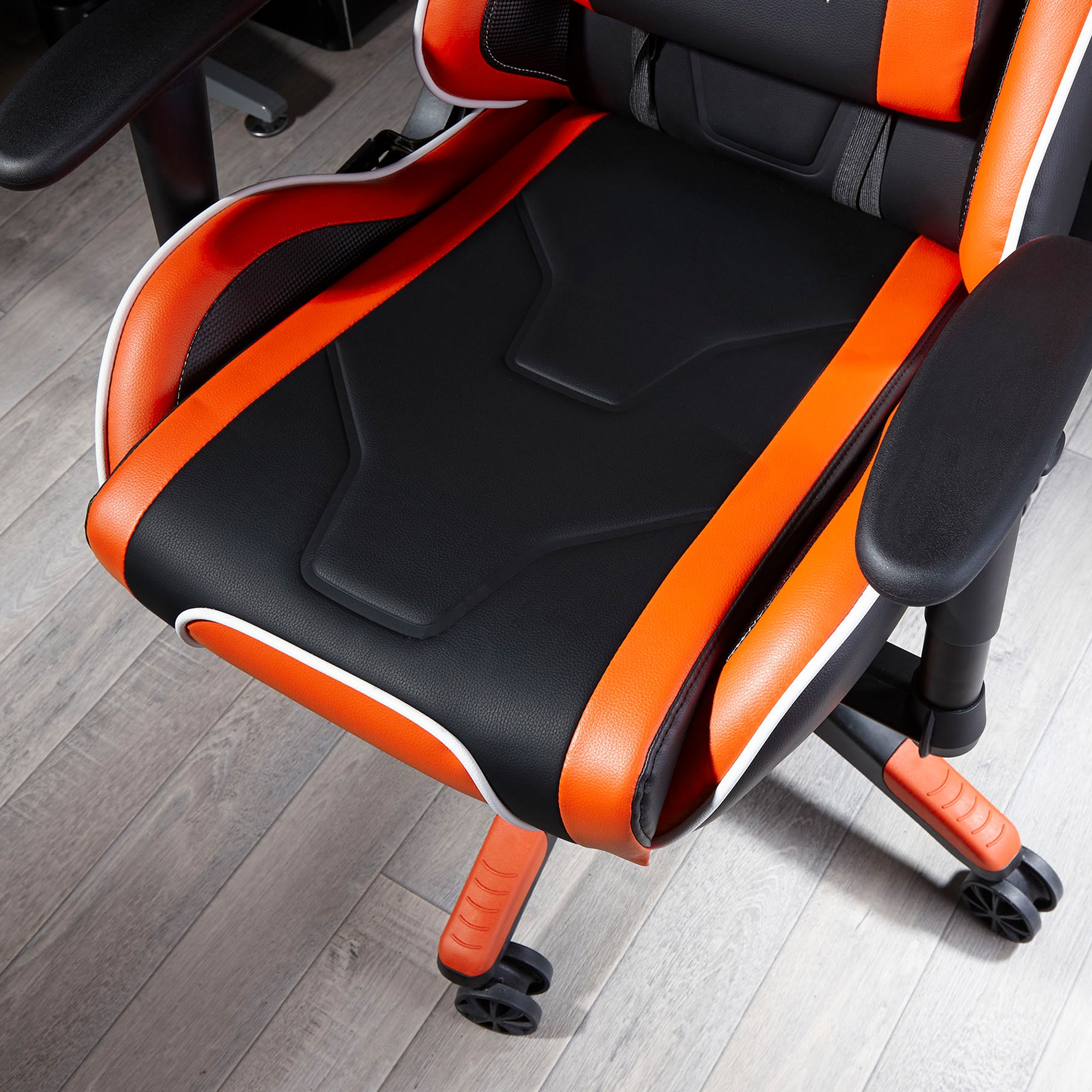 Schwarzer und orangefarbener Gaming-Stuhl auf einem Holzboden. Der Stuhl ist leer.