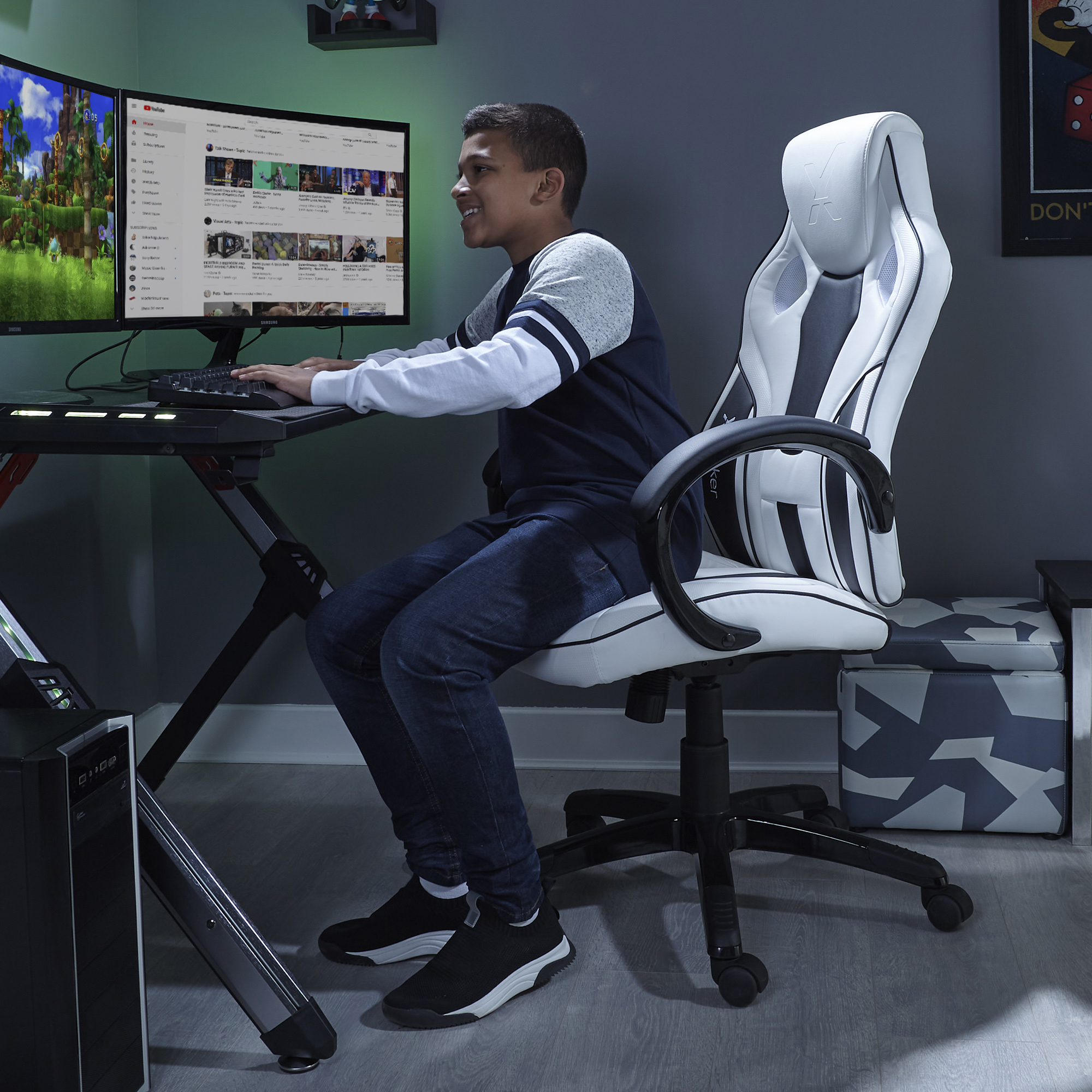 Teenager in Gaming-Stuhl vor Monitoren. Zeigt ein YouTube-Video und ein Spiel.