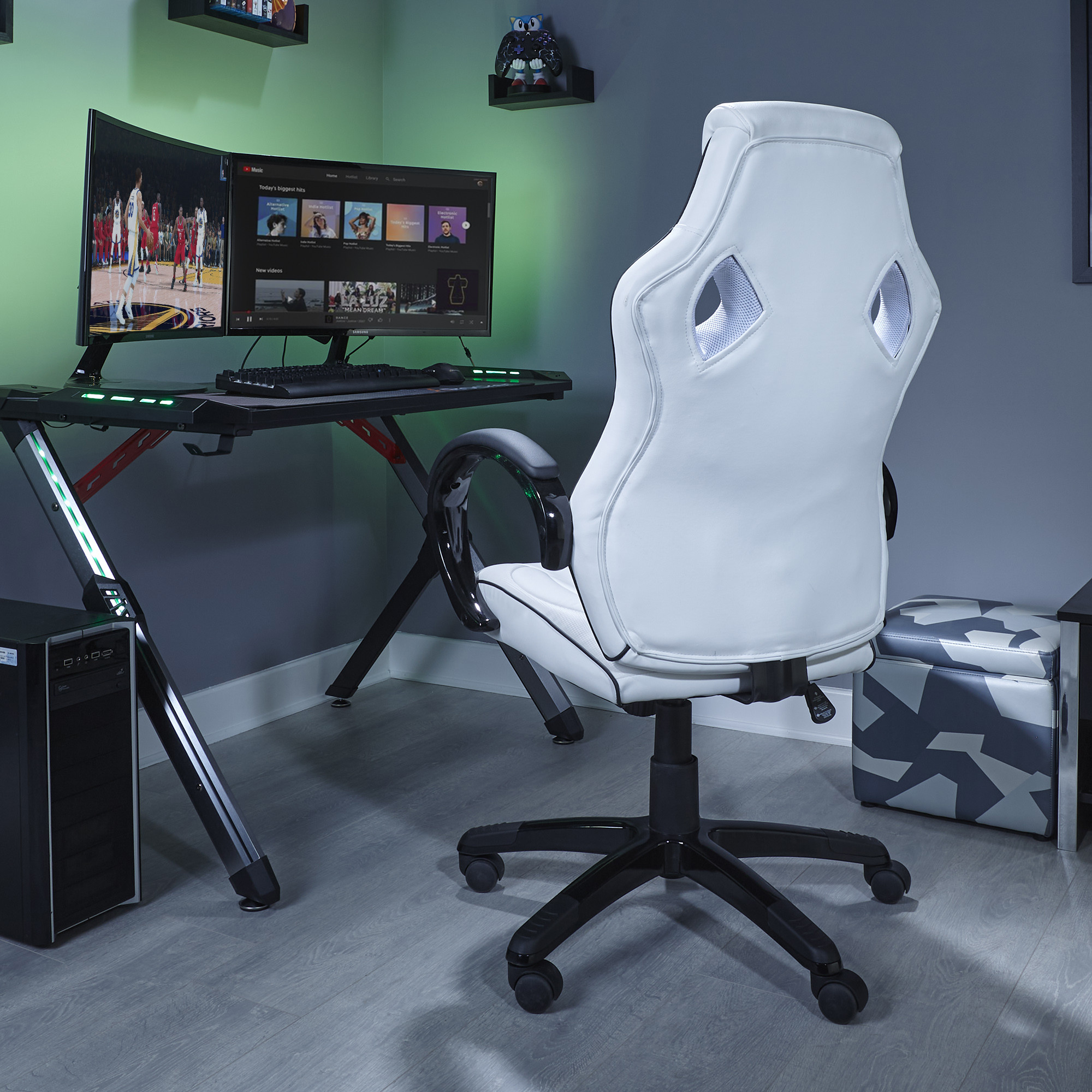 Gaming-Zimmer mit weißem Stuhl, schwarzem Schreibtisch mit zwei Monitoren und Computer.