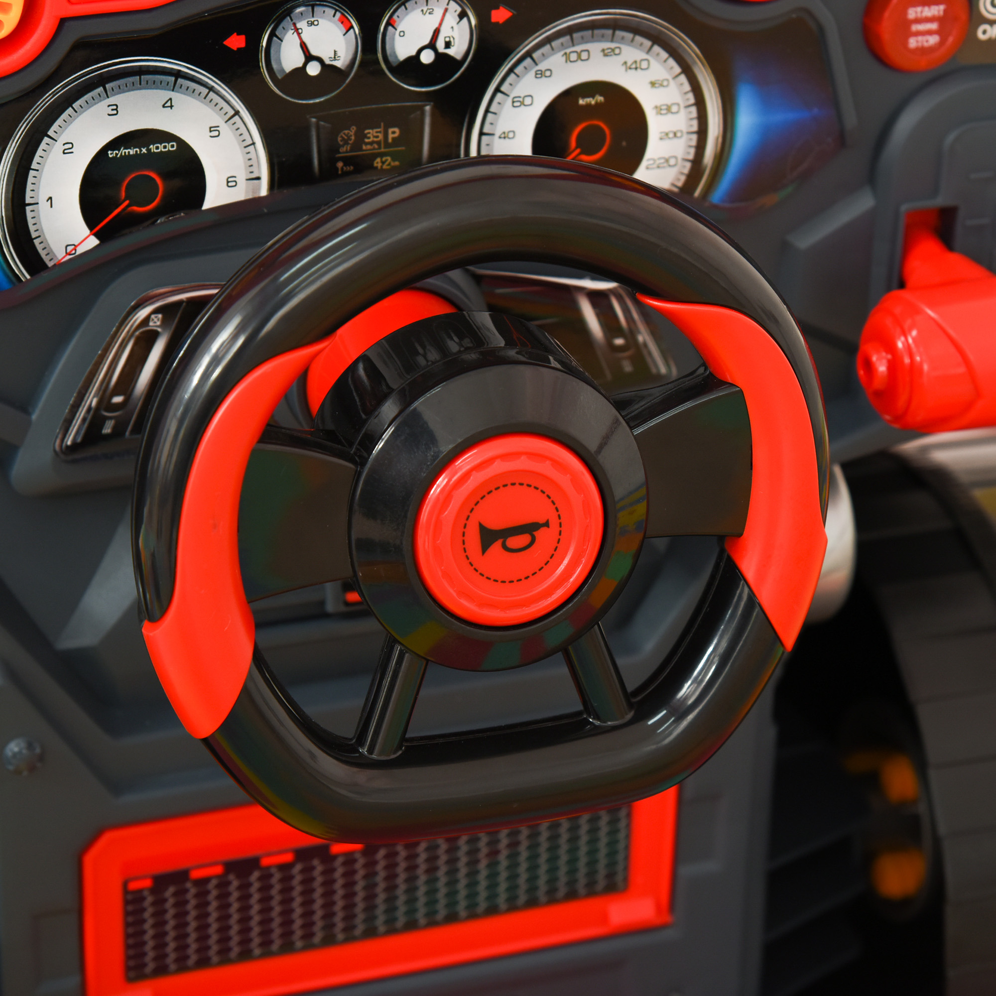 Volante negro y rojo con cuadro de instrumentos en el interior de un coche de juguete infantil.