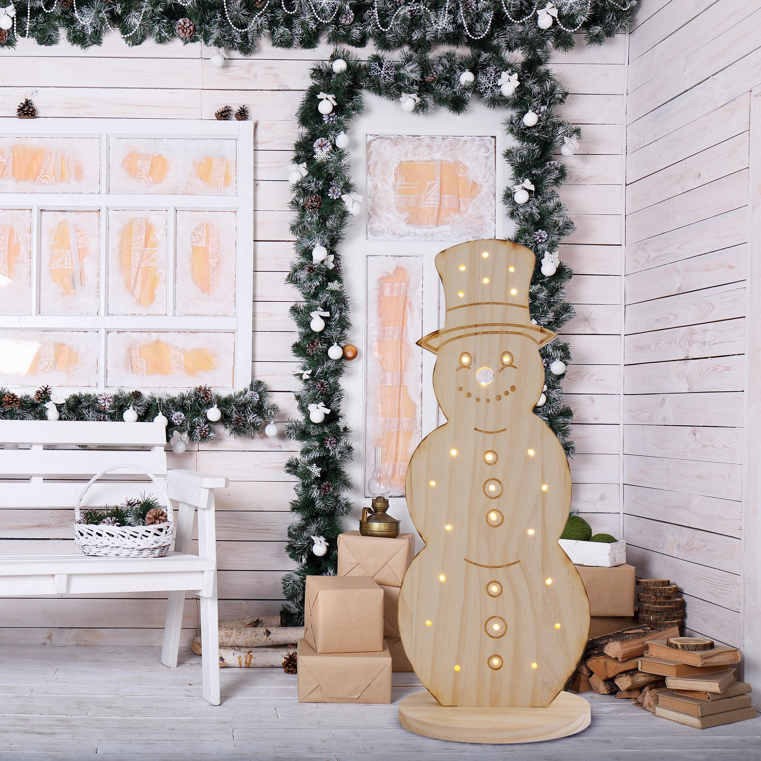 Weihnachtsschneemann aus Holz mit Lichtern vor weißer Wand.