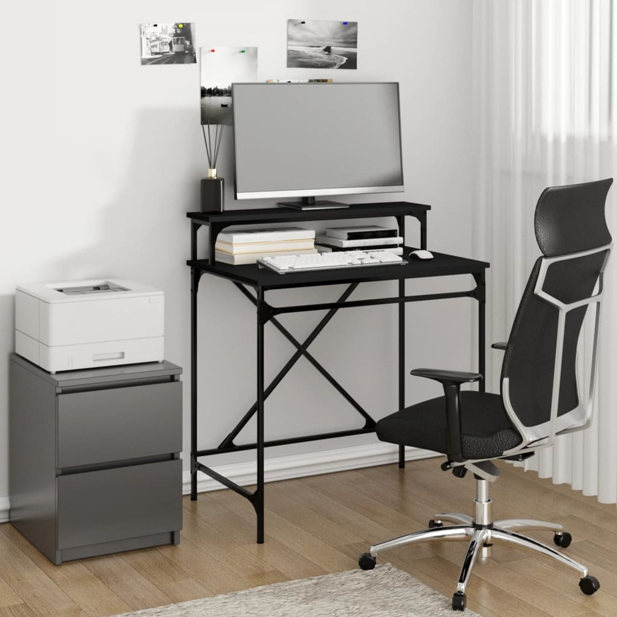 Ein schwarzer Schreibtisch mit Computer. Es gibt einen Drucker, einen Aktenschrank und einen schwarzen Bürostuhl.