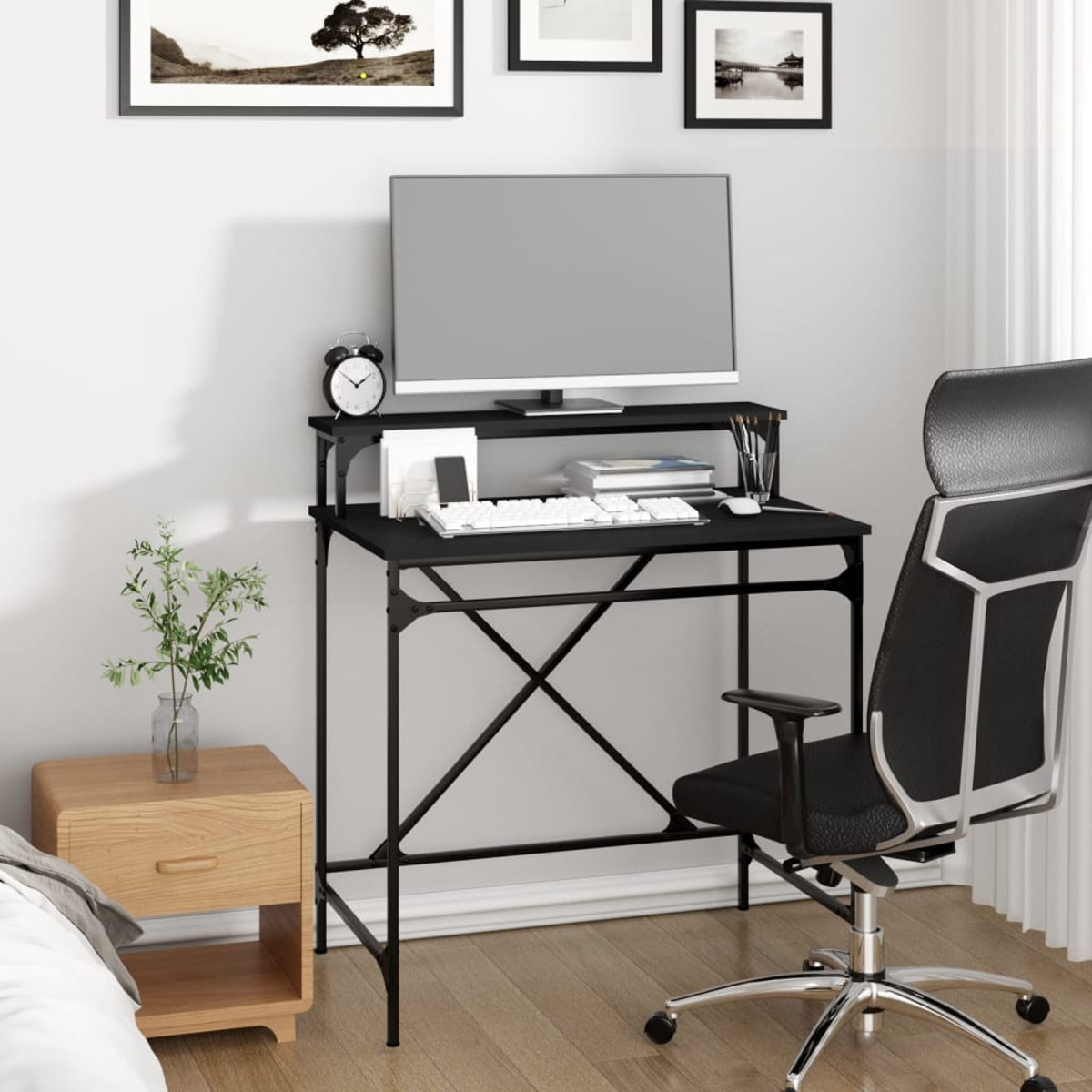 Ein schwarzer Schreibtisch mit Monitor, Tastatur und Büromaterial in einem Raum. Eine Topfpflanze und ein Stuhl sind ebenfalls vorhanden.