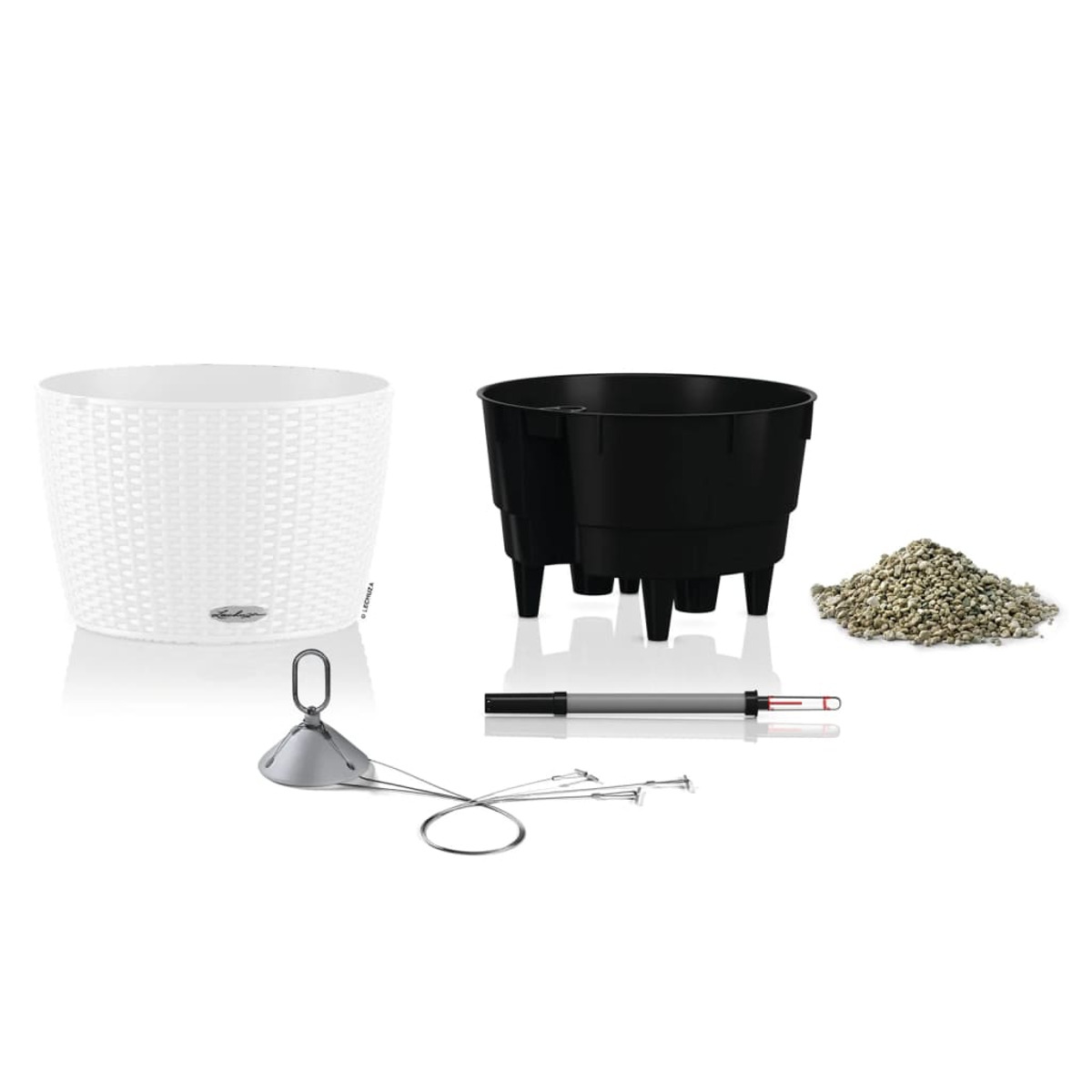 Configuration de plantes en pot avec pot blanc, pot noir et outils de jardinage.