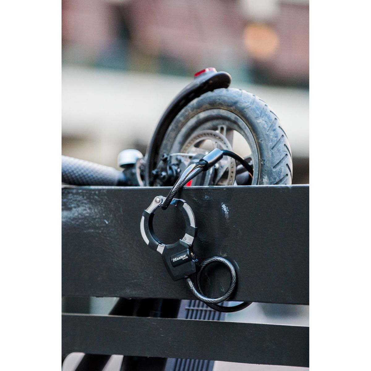 Ruota di e-scooter assicurata con un lucchetto a cavo Master Lock nero.