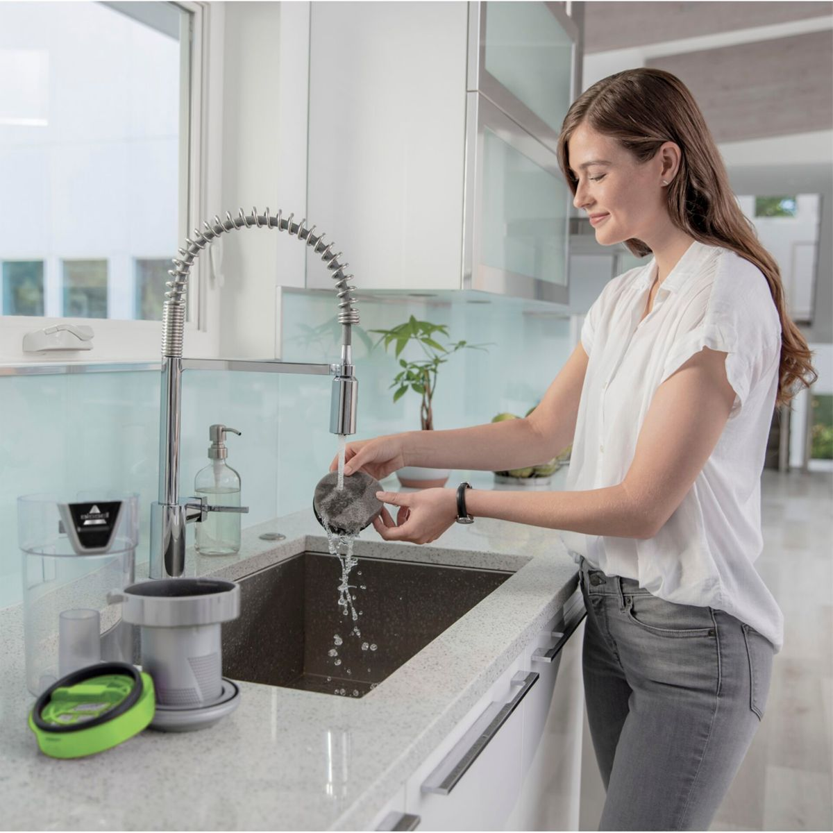 Frau wäscht einen Filter unter einem Waschbecken. Wasser läuft.
