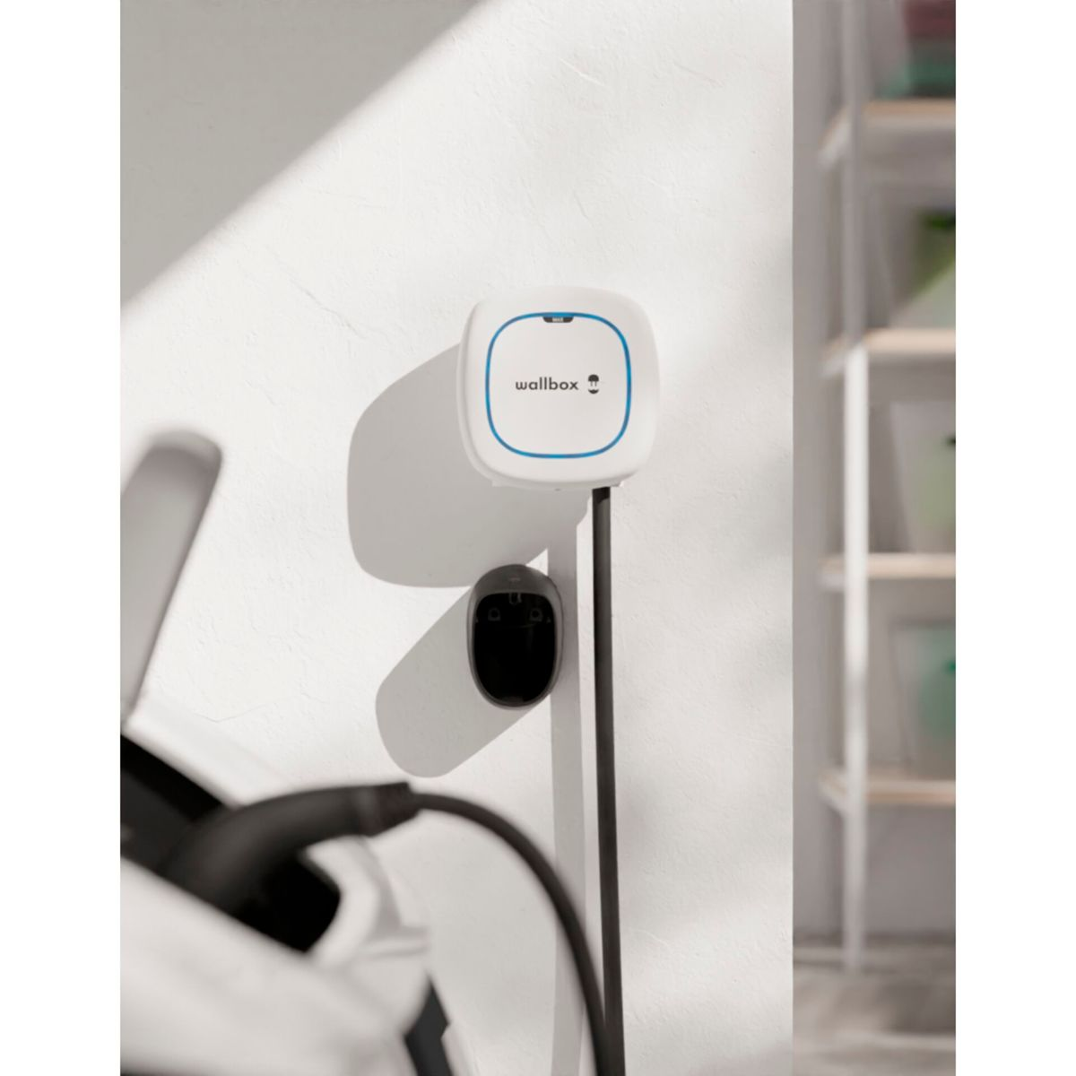 Weißer Wallbox-Charger mit Ladekabel. Schwarzer Ladeanschluss. Weißer Hintergrund.