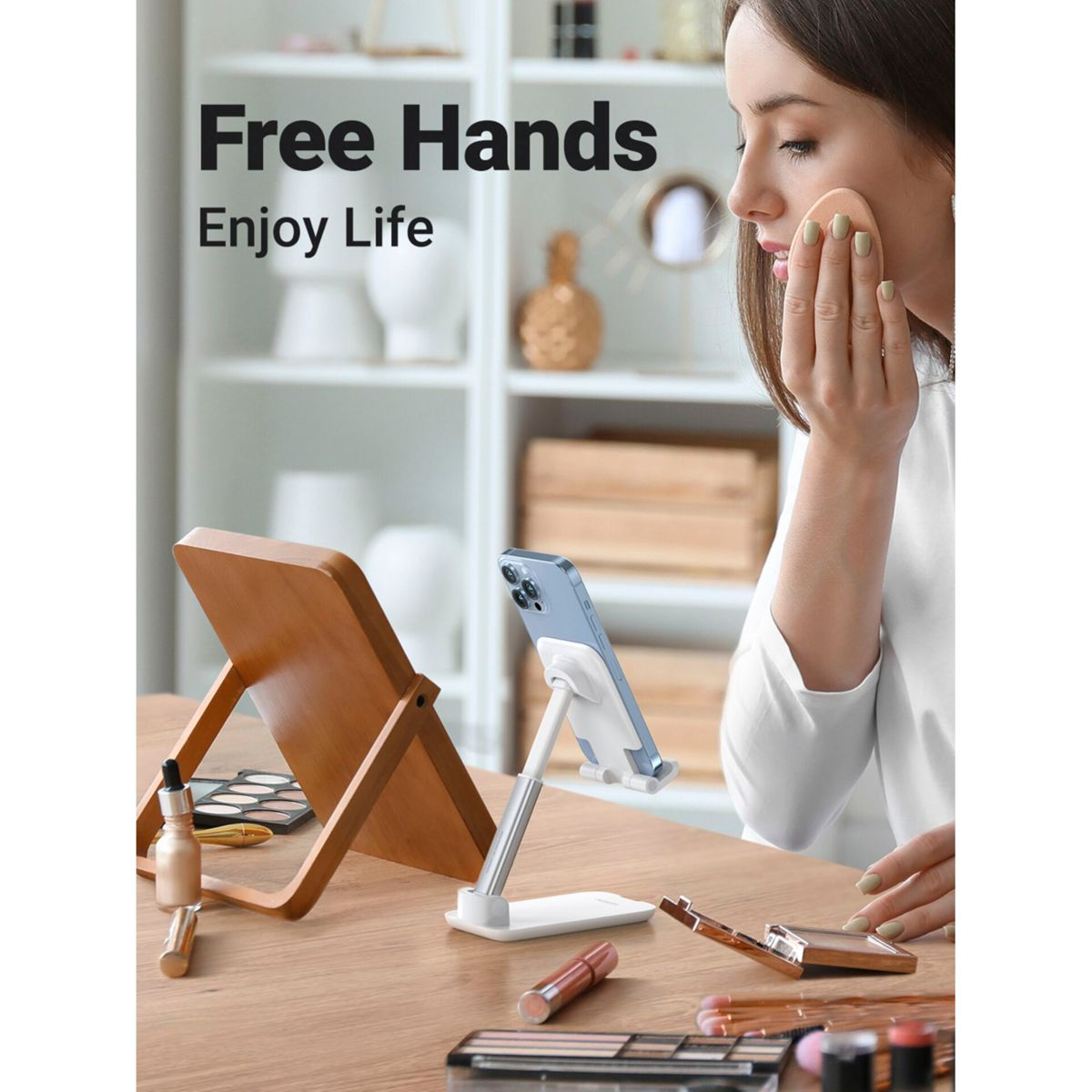 Kobieta nakładająca makijaż z lusterkiem i stojakiem na telefon na drewnianym stole. Widoczne są też produkty.