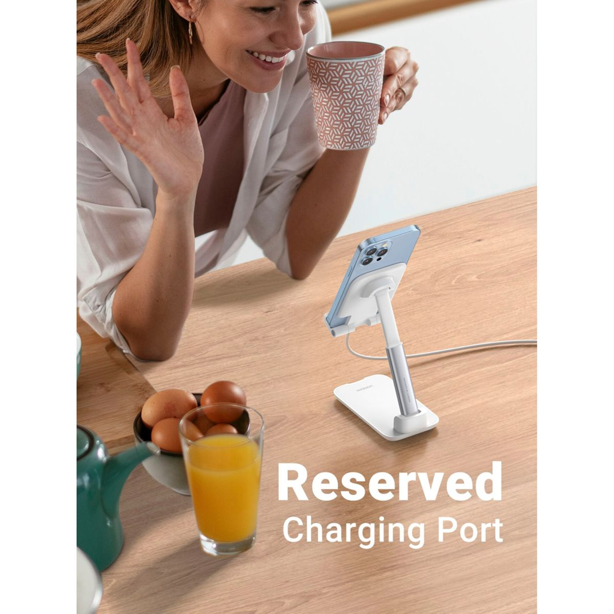 Kobieta korzystająca z telefonu na stojaku, jajka i sok na drewnianym stole. Tekst mówi: "Reserved Charging Port".