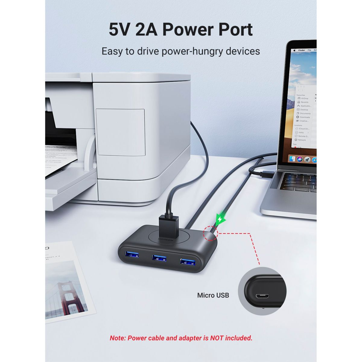 Czarny koncentrator USB z trzema niebieskimi portami, podłączony do laptopa i drukarki.