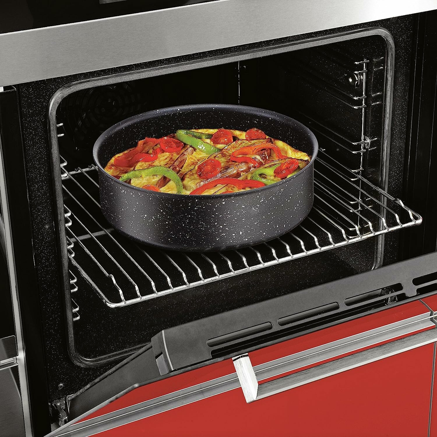 Backofeninnenraum mit einer Pizza in einer schwarzen Backform. Roter Backofeninnenraum.