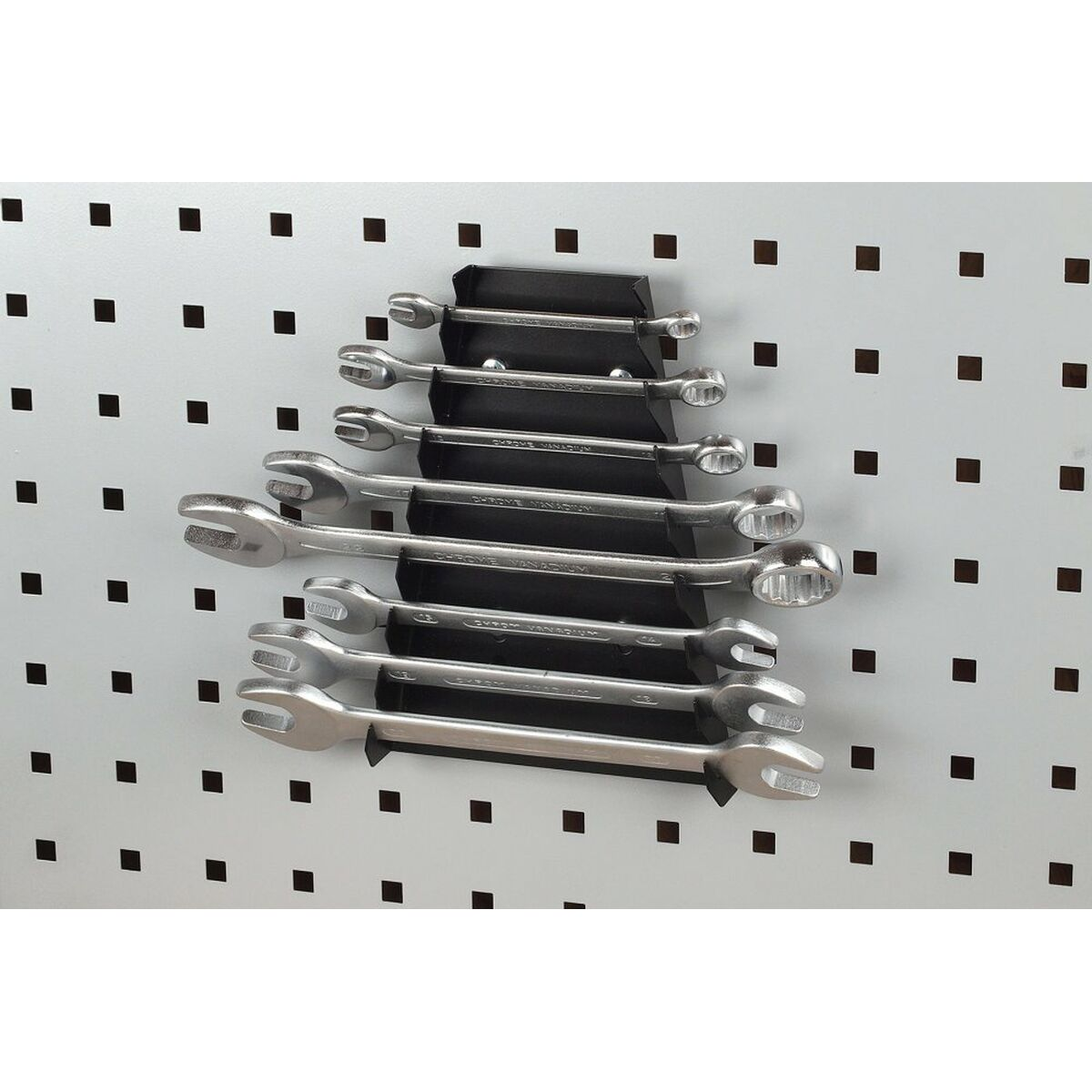 Un juego de llaves en un soporte. Están en una placa de metal gris perforada.