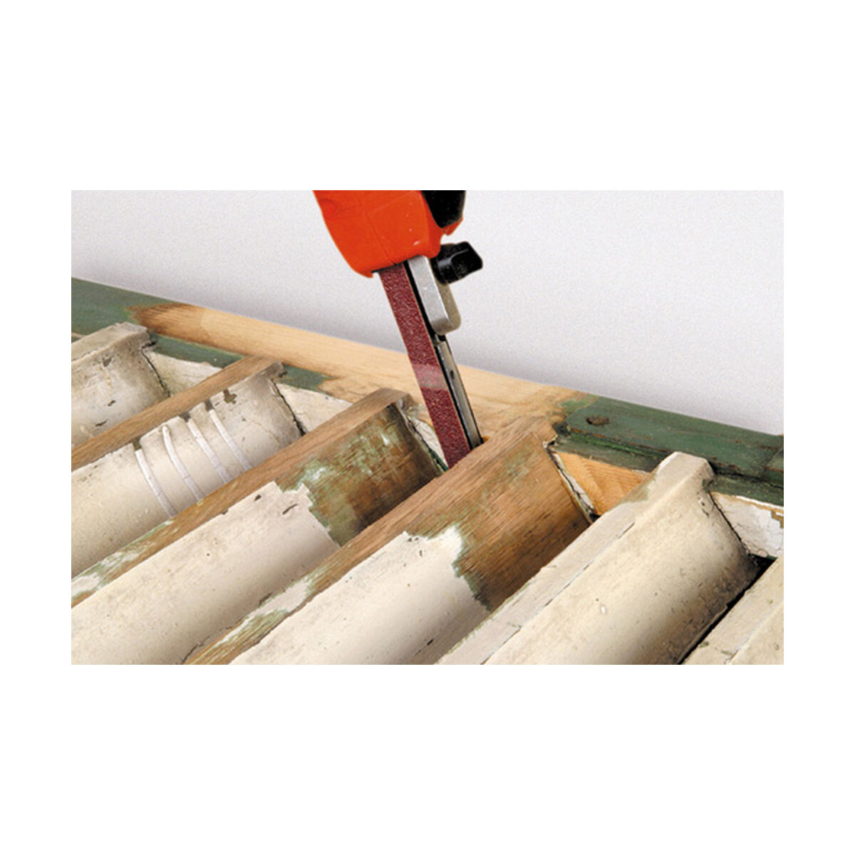 Una lijadora en uso, lijando una estructura de madera con superficie pintada de blanco y verde.