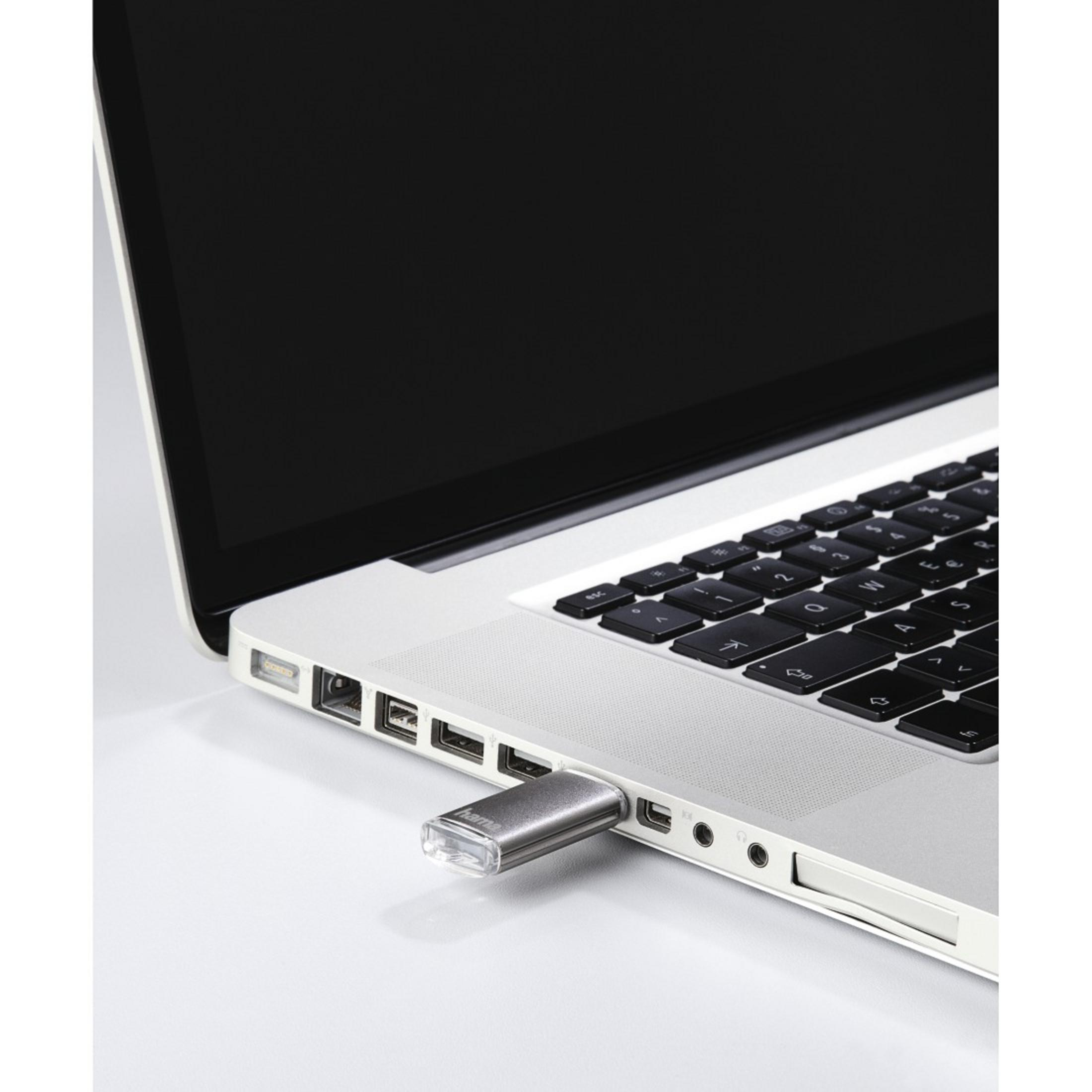 Laptop z srebrnym pendrive'm włożonym do portu USB. Czarne klawisze i ekran.