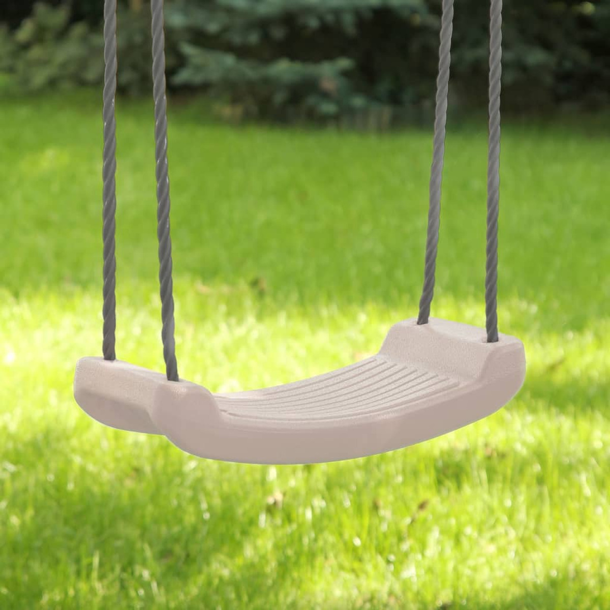 Schaukel von Seilen hängend vor grünem Gras.