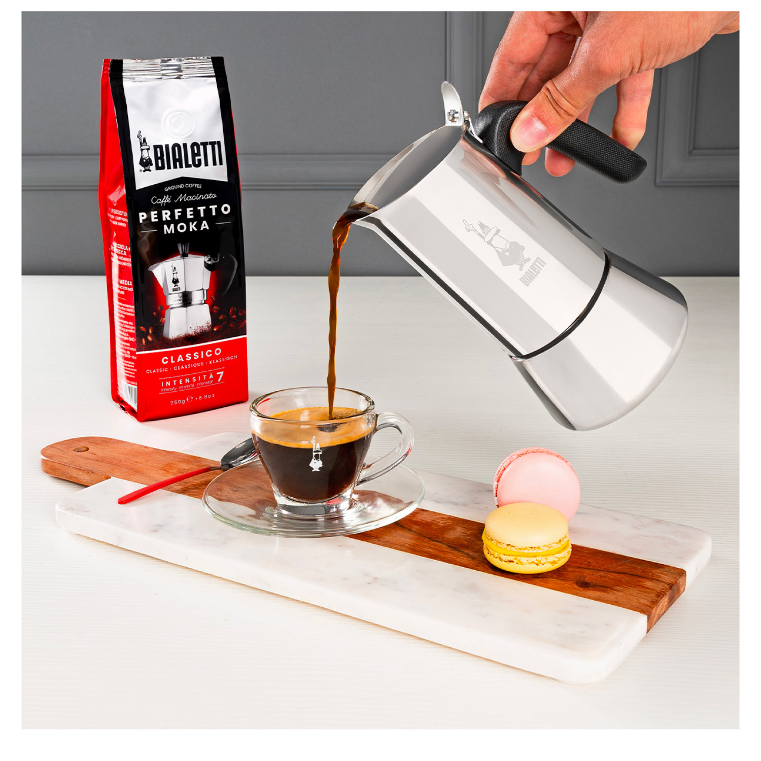 Kawa wlewana ze srebrnego dzbanka do szklanki, z makaronikami.