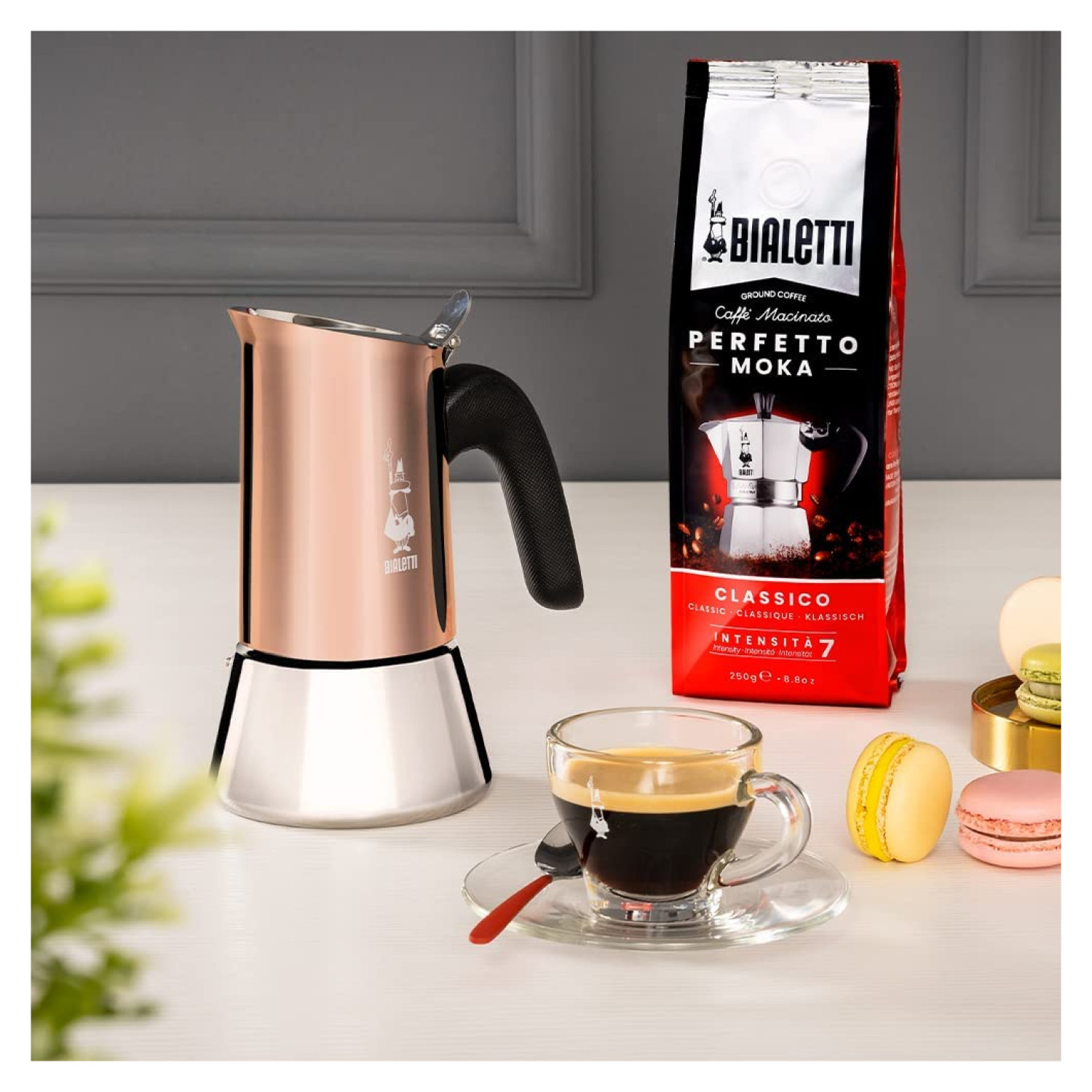 Miedziana kawiarka Bialetti Moka, torebka kawy, espresso, makaroniki na stole.