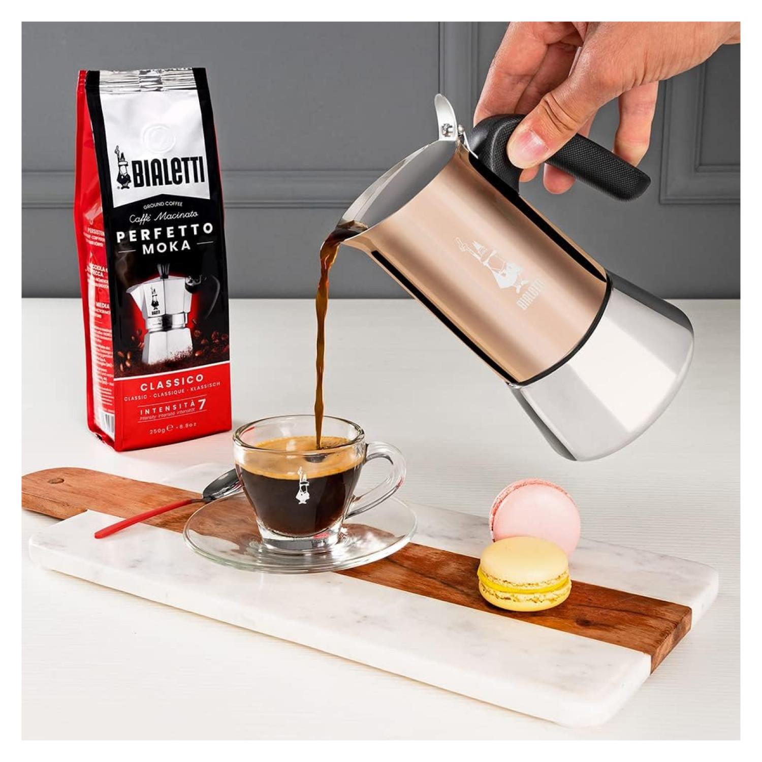 Osoba nalewa kawę z różowego złota ekspresu Bialetti Moka do szklanki.