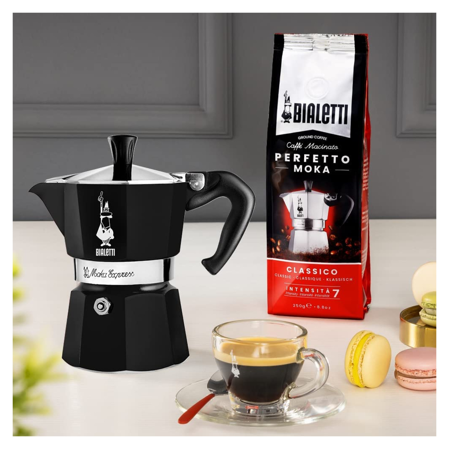 Czarny kawiarka Bialetti, torba kawy, espresso w szklance, makaroniki.