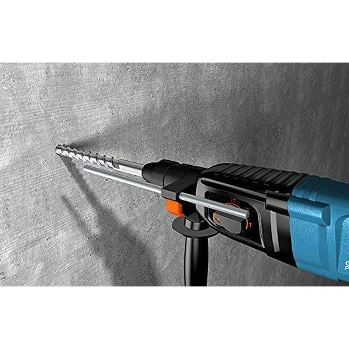 Taladro azul y negro, taladrando una pared de hormigón gris. Primer plano.