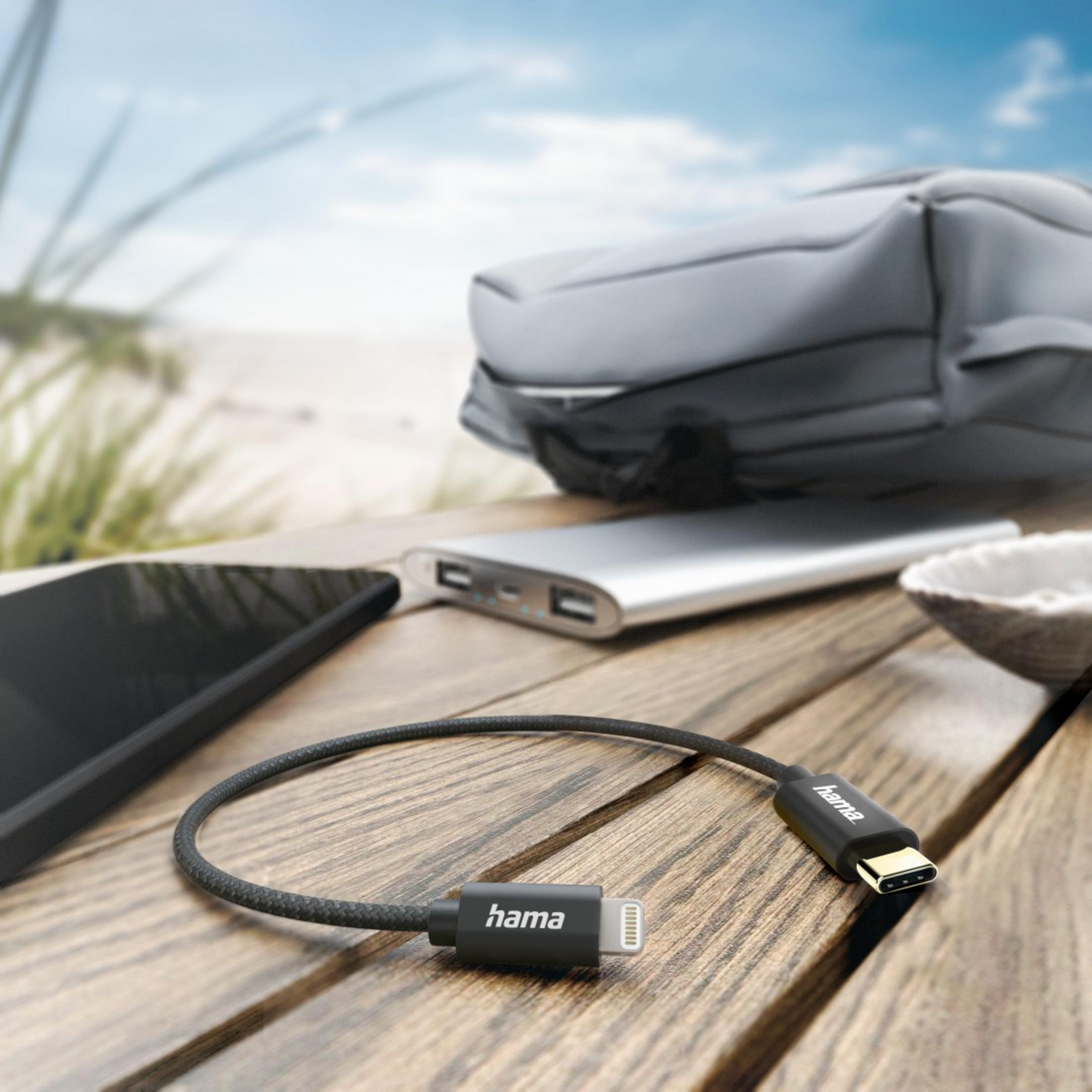 USB-C-auf-Lightning-Kabel. Schwarzes Kabel, graue Tasche, Smartphone und eine silberne Powerbank.