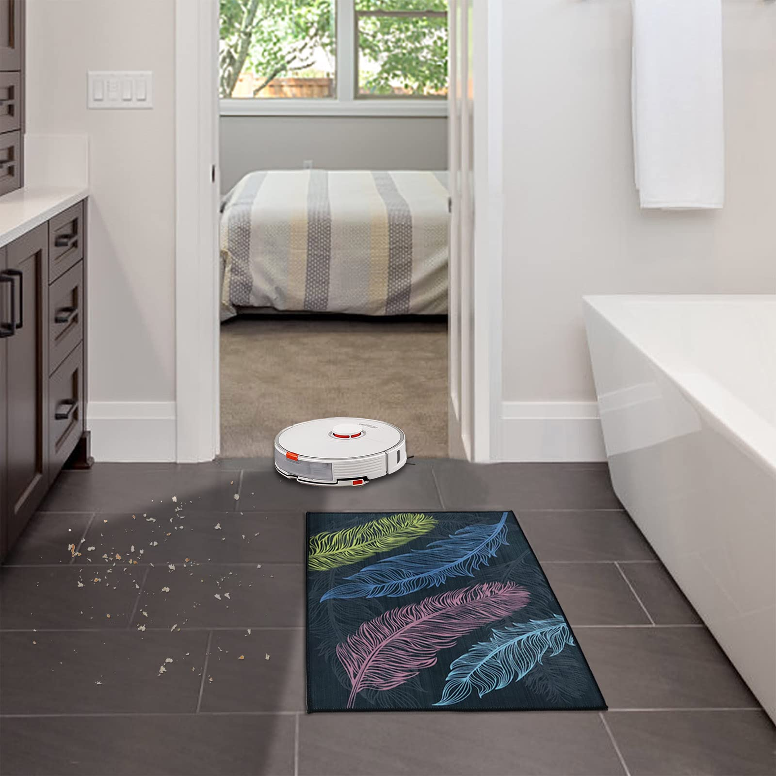 Robot sprzątający na ciemnej podłodze z płytek, dywan z piórami i łazienka w tle.