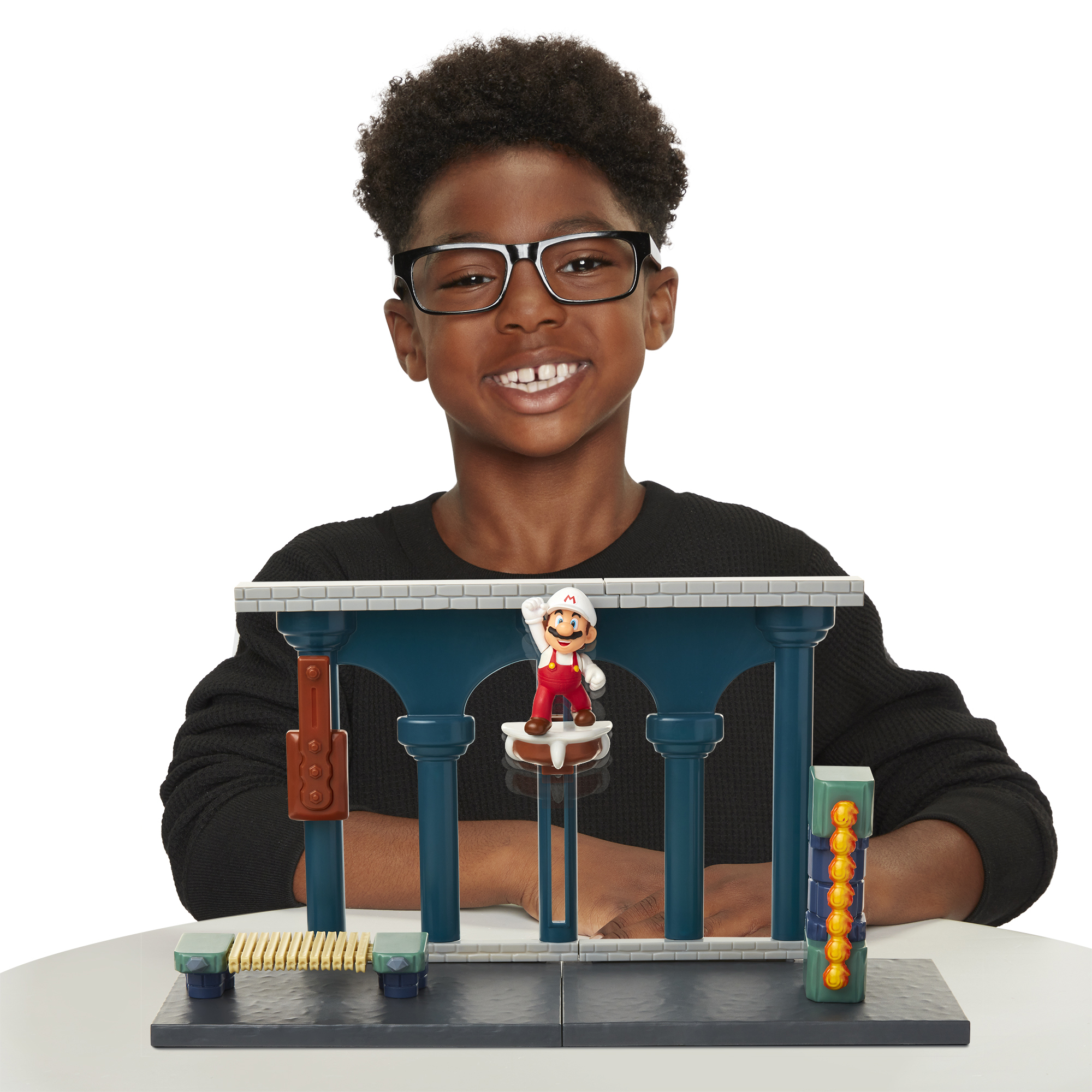 Niño con gafas sonríe, mirando un juguete de Super Mario.