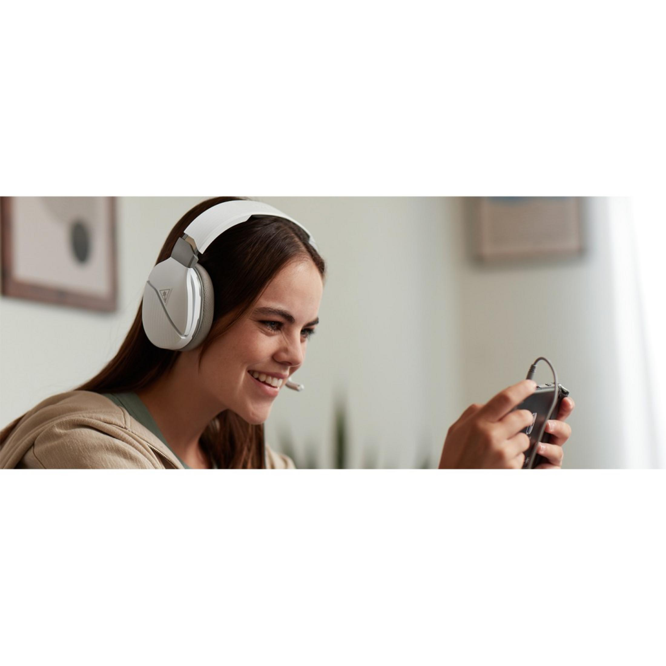 Kobieta w słuchawkach uśmiecha się, trzymając kontroler do gier. Gra w grę.