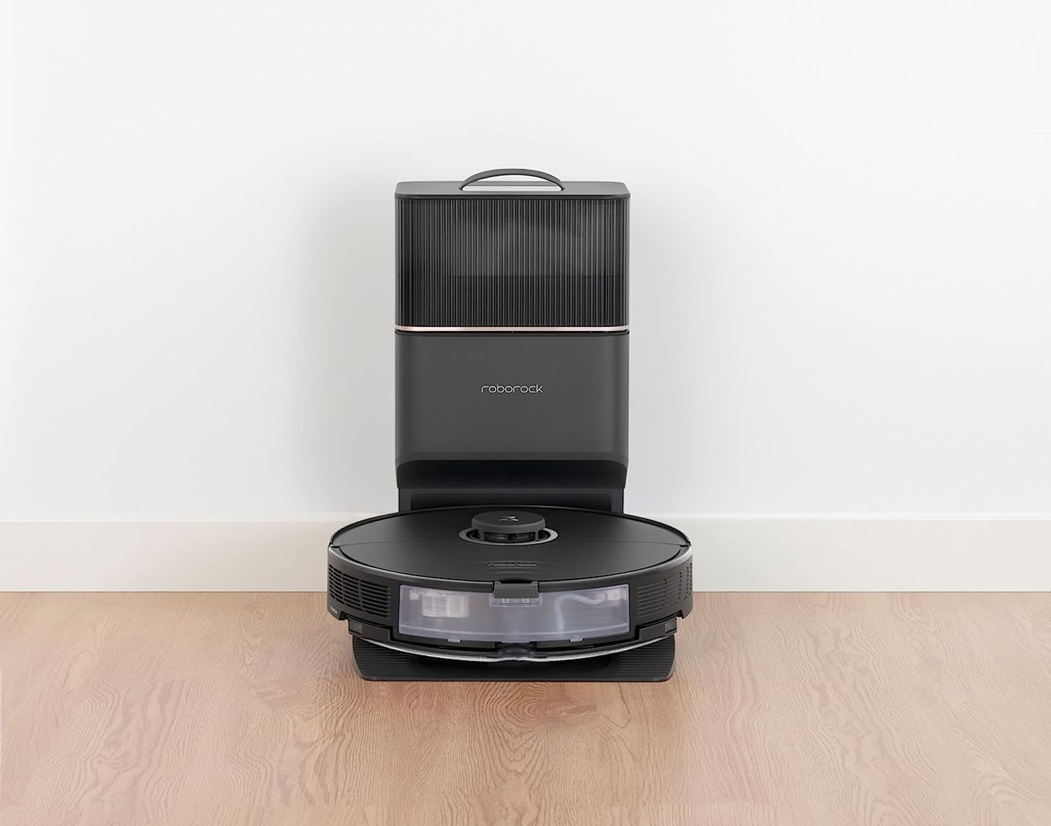 Czarny i srebrny odkurzacz automatyczny ze stacją ładującą na białej podłodze.