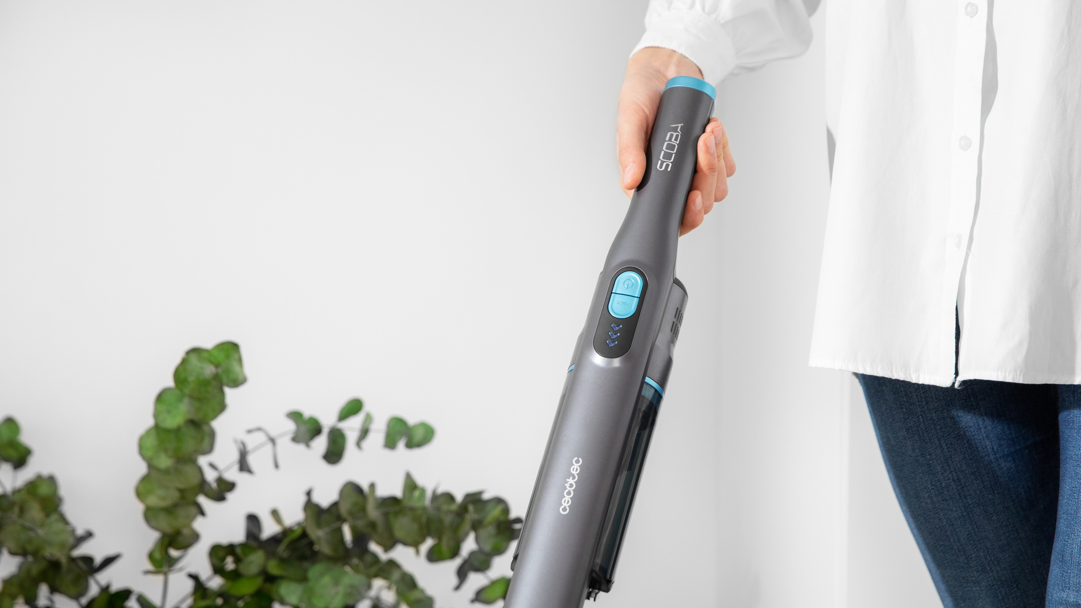 Una persona sosteniendo una aspiradora Cecotec Scooba gris y azul.