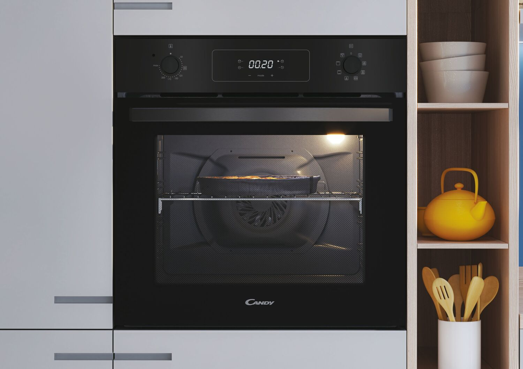 Horno en una cocina, puerta abierta, con un pastel dentro. Armarios y estante con utensilios.
