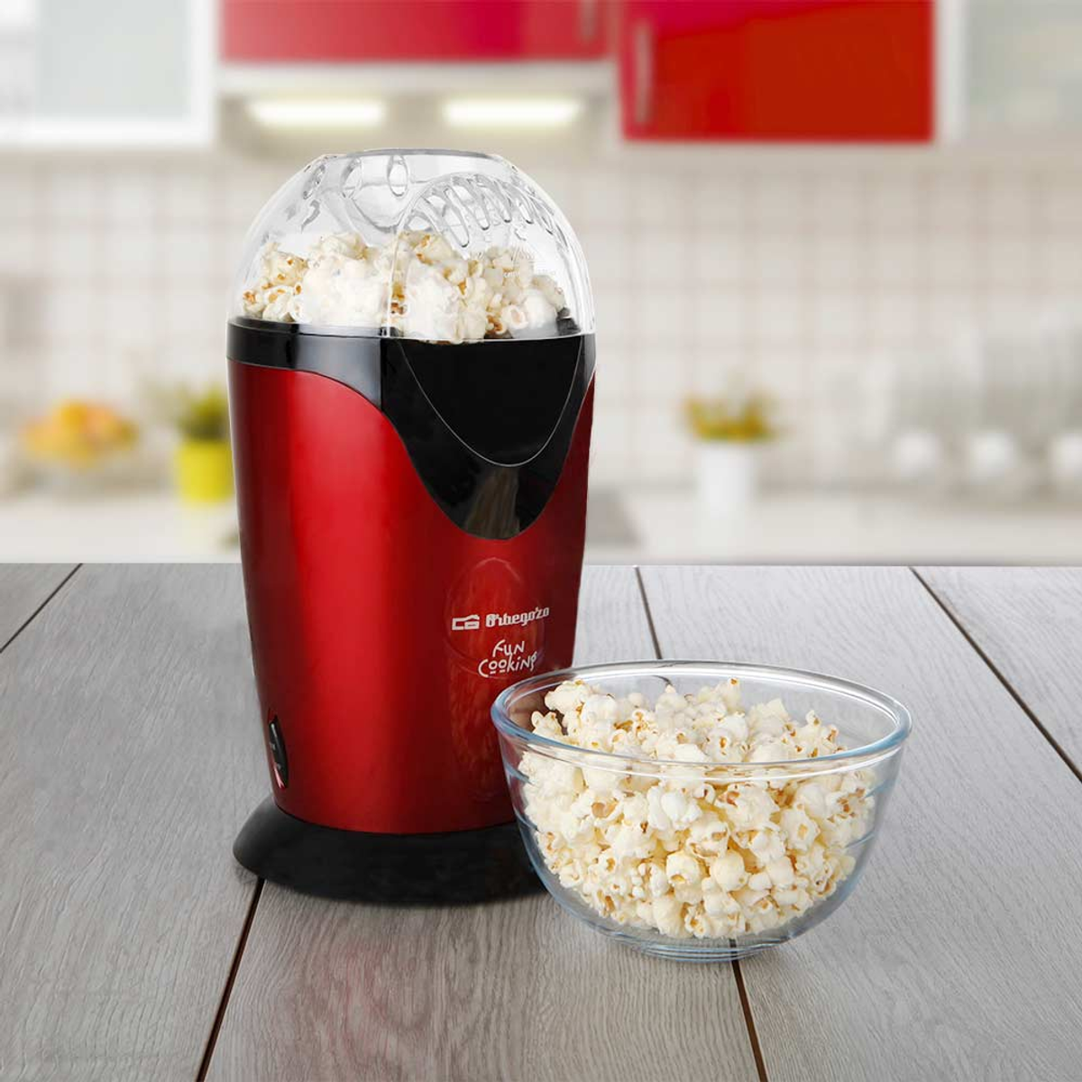 Máquina de palomitas roja con palomitas dentro y un tazón lleno de palomitas.