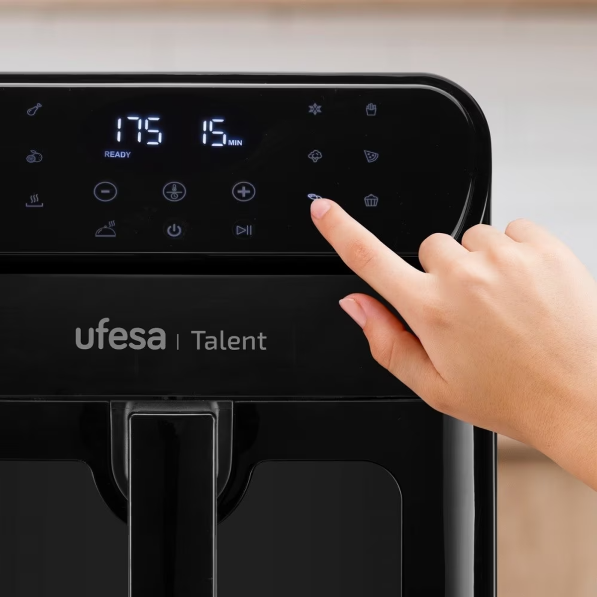 Una mano preme un pulsante sul pannello di controllo di una friggitrice ad aria nera, mostrando 175°.