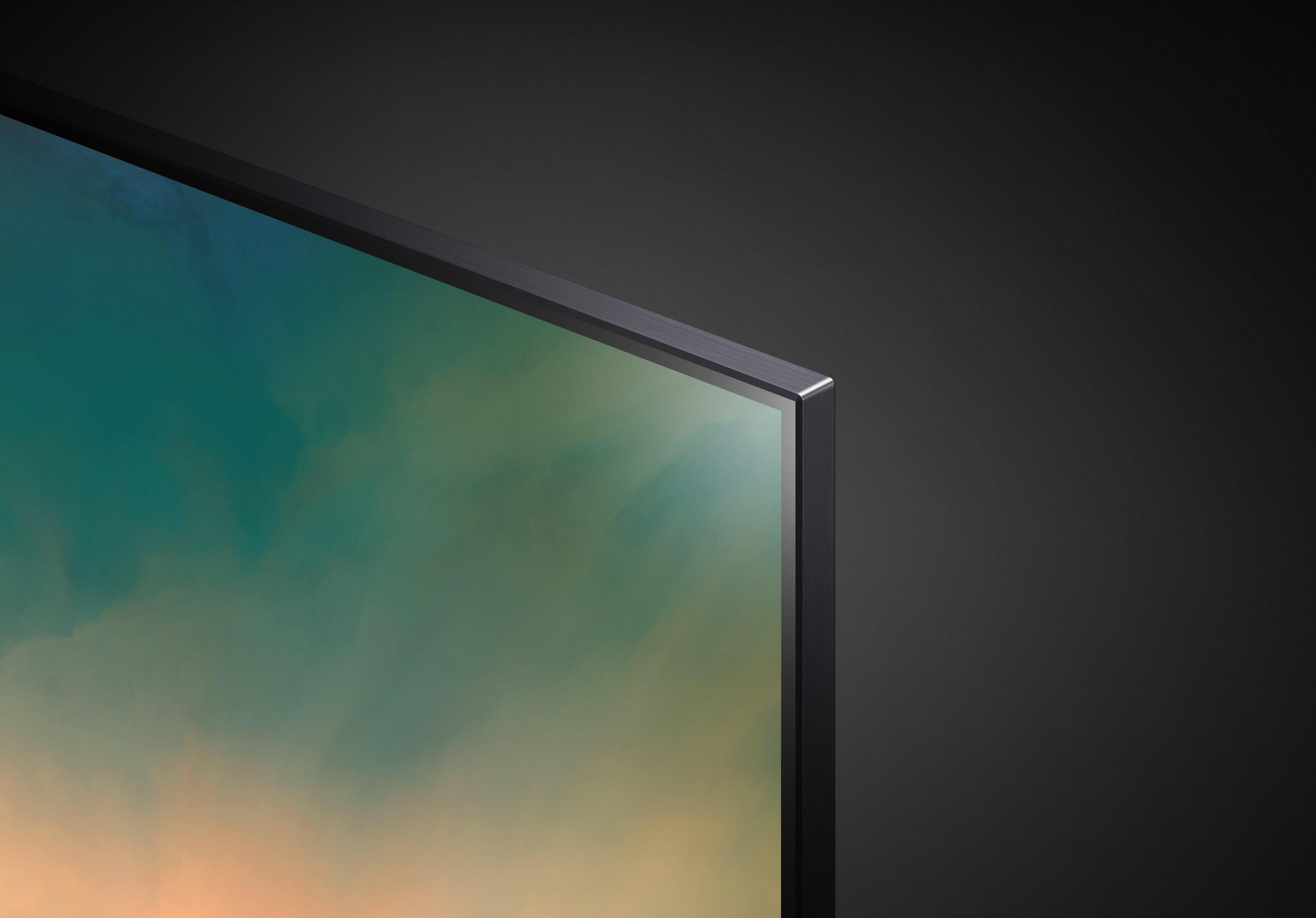 Zbliżenie rogu ekranu telewizora z ciemnoszarą ramką na ciemnoszarym tle.