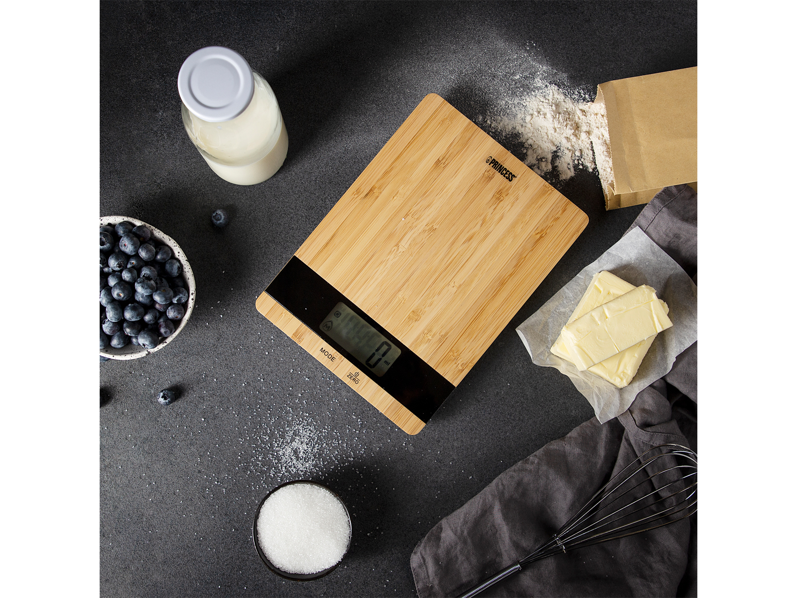 Waga do krojenia z bambusa ze składnikami: jagodami, mąką, cukrem, masłem.