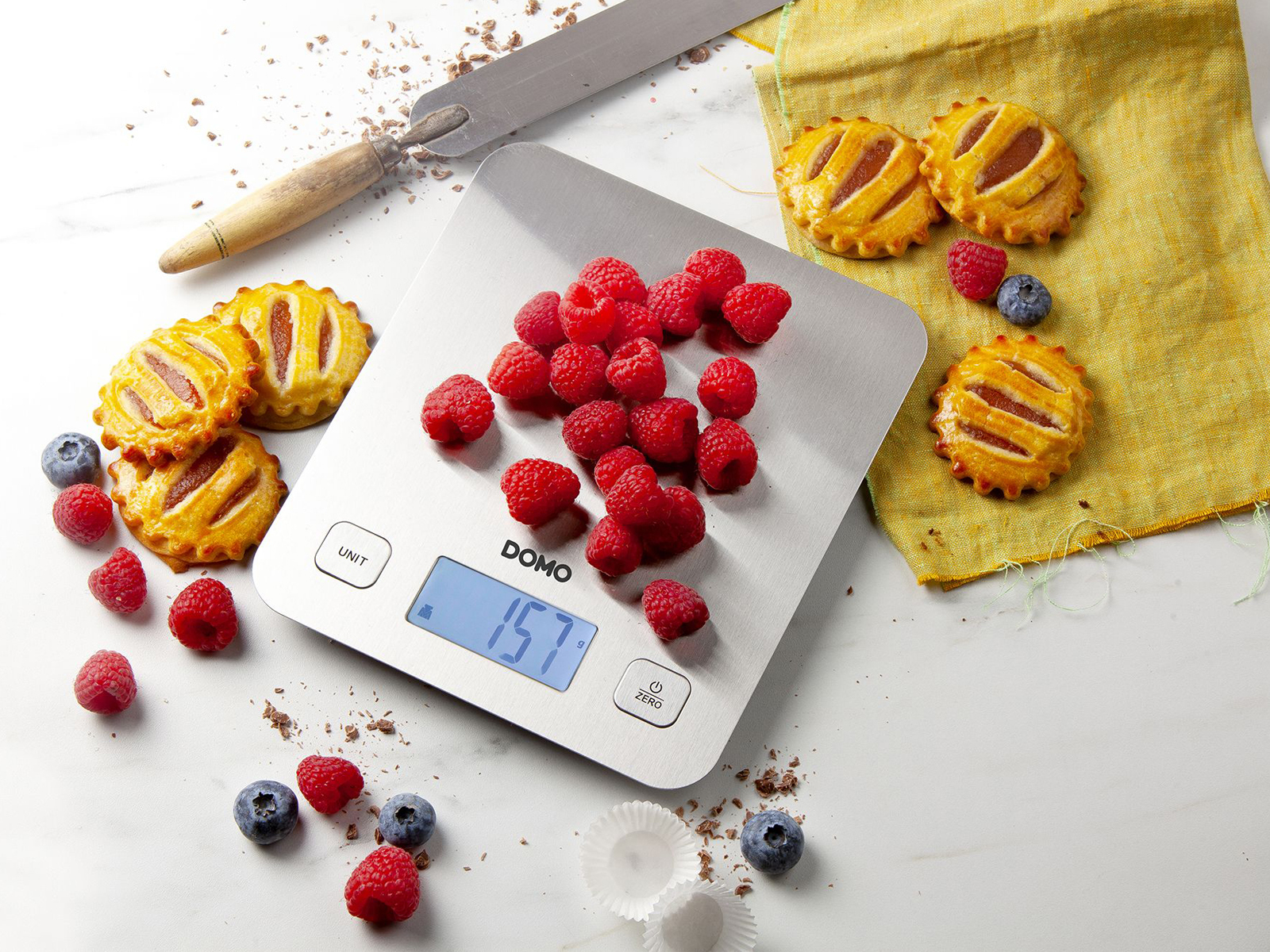 Waga z malinami i jagodami. Ciastka wokół wagi.