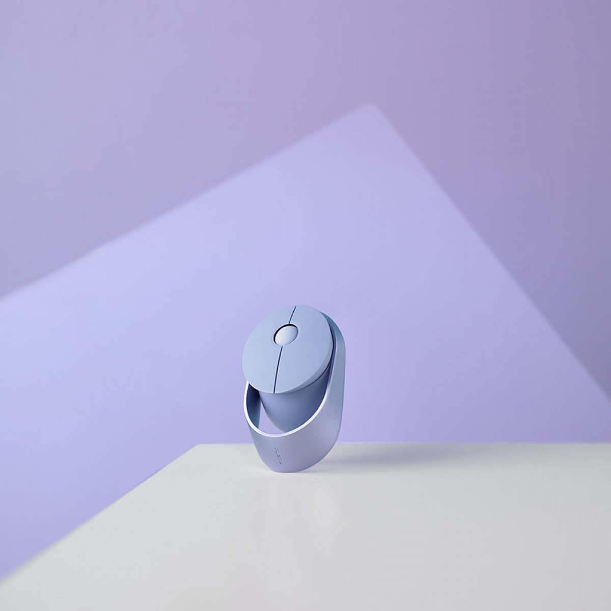 Un ratón de computadora azul claro. Descansa sobre una superficie blanca con fondo morado.