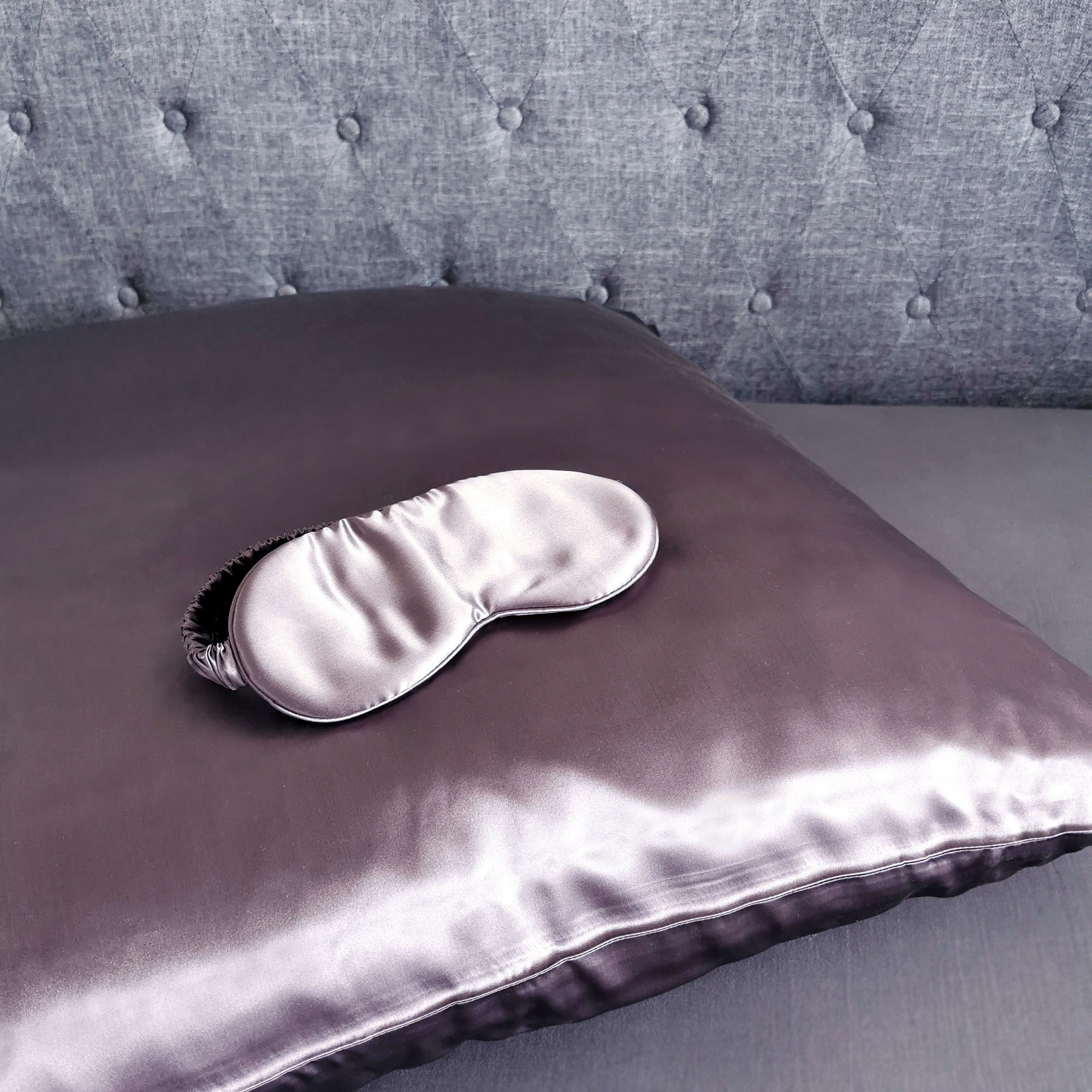 Lila Kissen mit passender Augenmaske. Graues getuftetes Kopfteil.