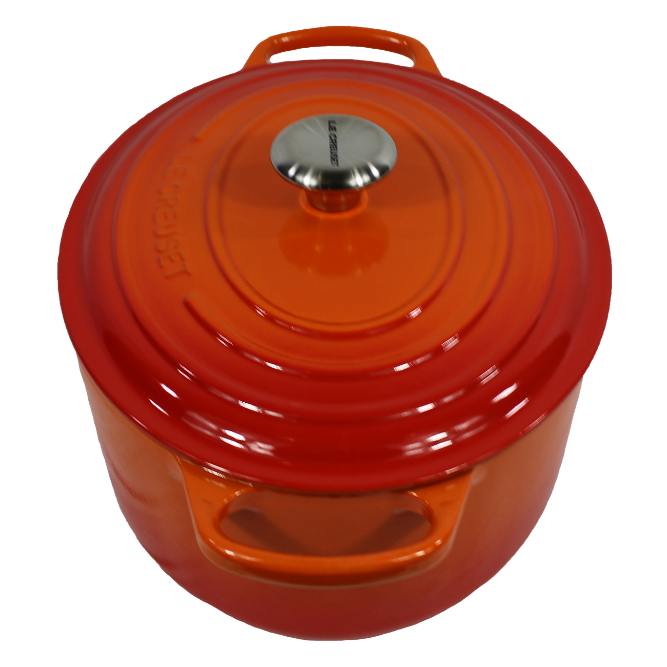 Une cocotte en fonte Le Creuset orange avec un couvercle, vue de dessus, sur fond blanc.