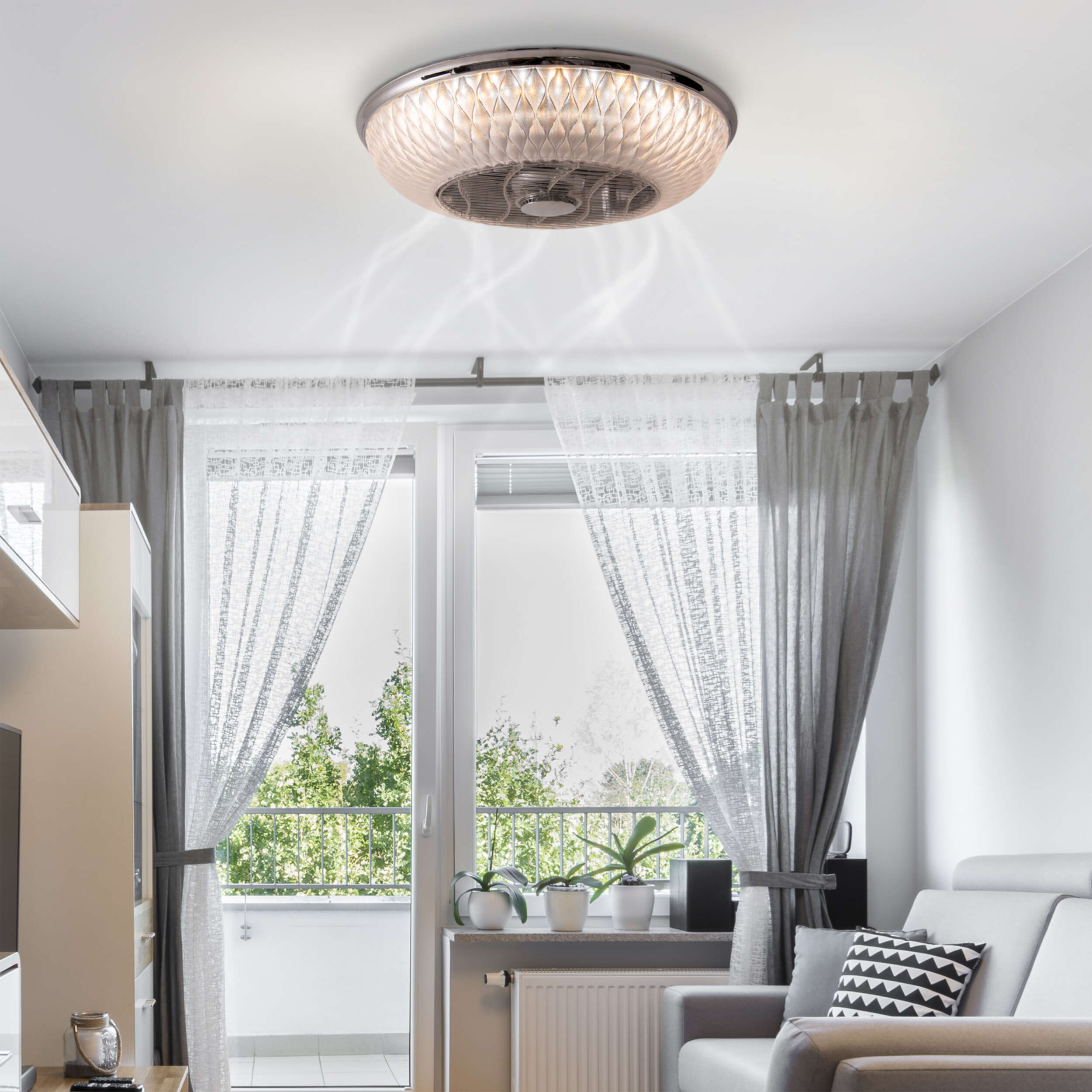 Deckenventilator mit Lichtern in einem Raum. Licht scheint vom Ventilator. Graue Vorhänge und Sofa.