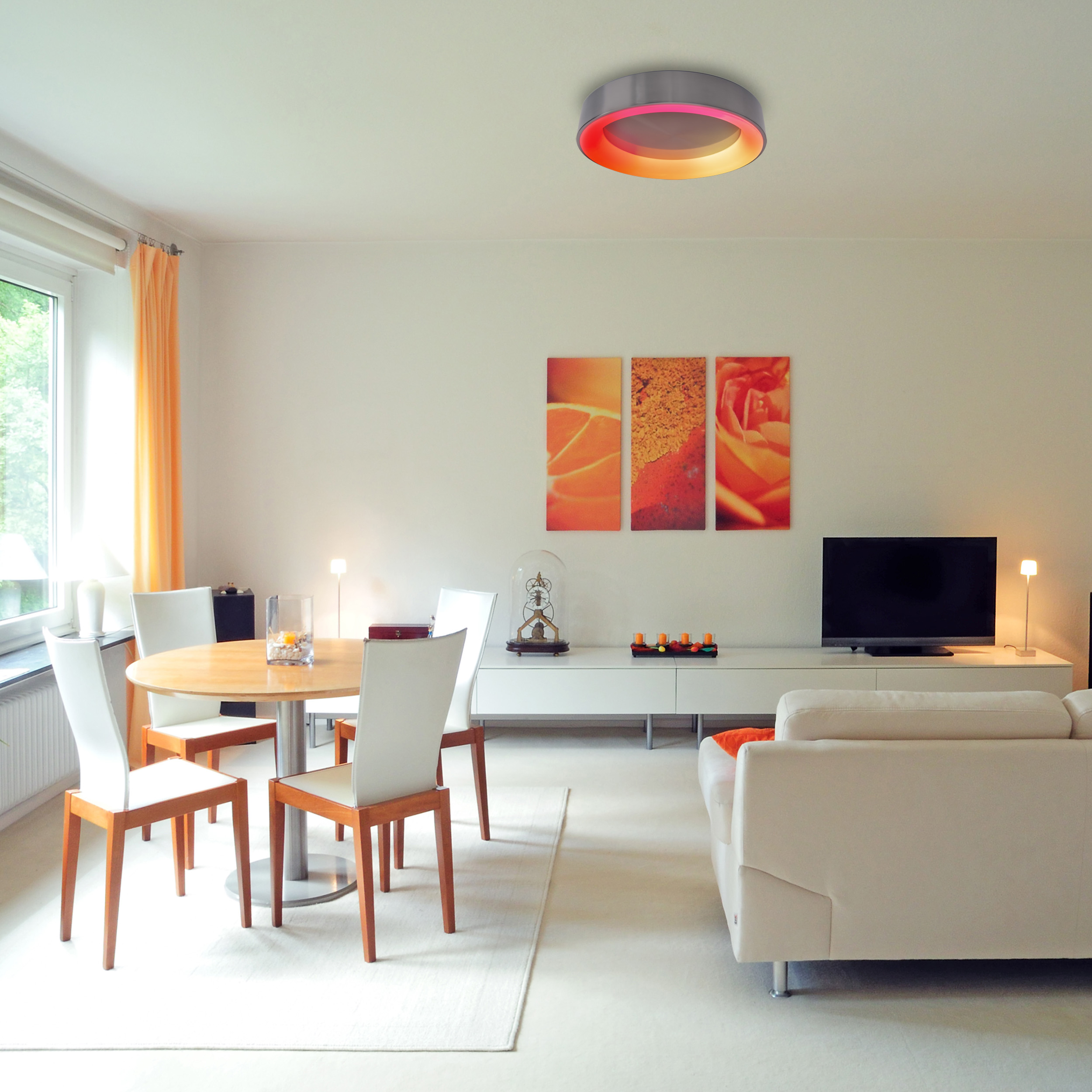 Wohnzimmer mit rundem Tisch, Sofa und Deckenleuchte.