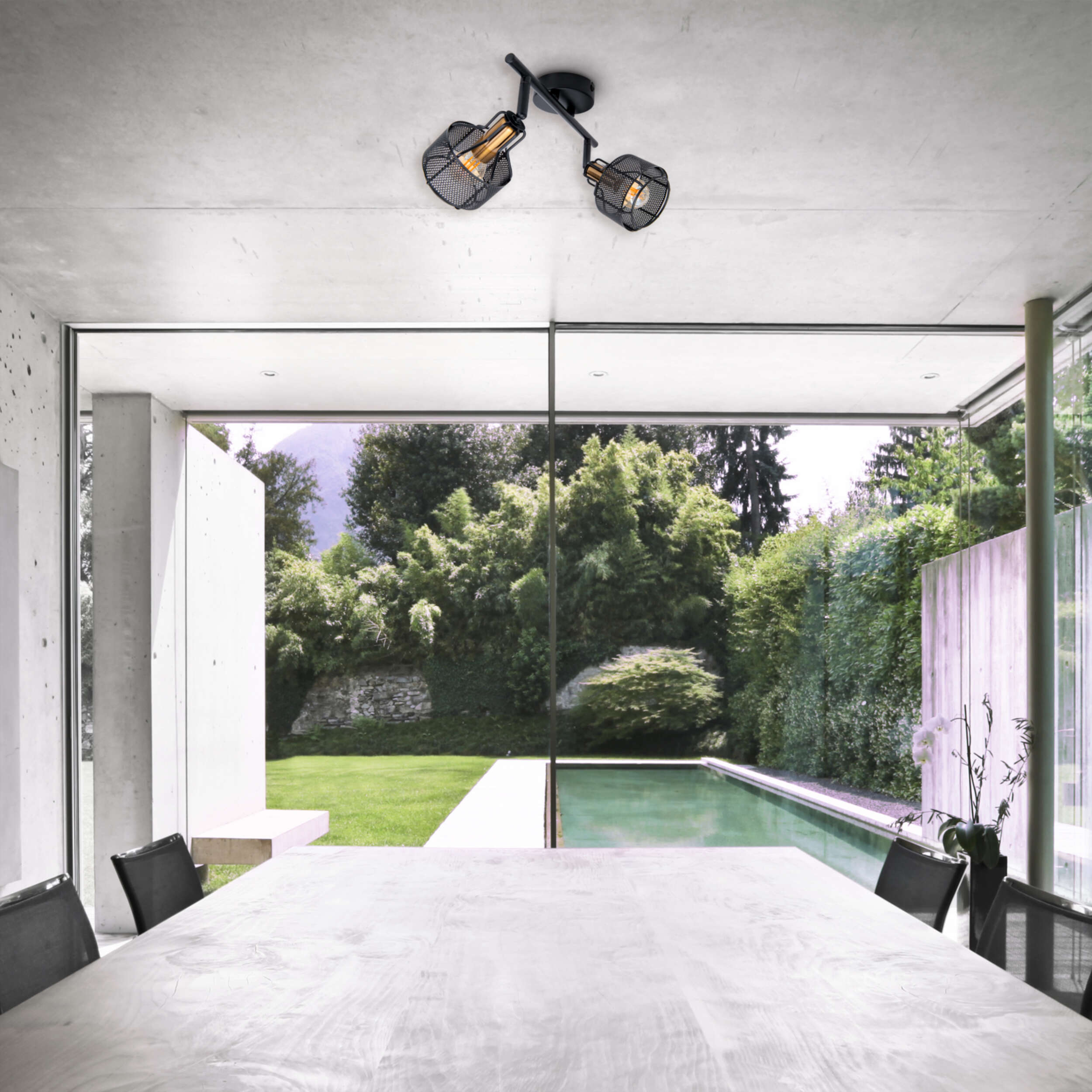 Esszimmer mit großem Fenster mit Blick auf Pool und Bäume. Zwei schwarze Strahler hängen.