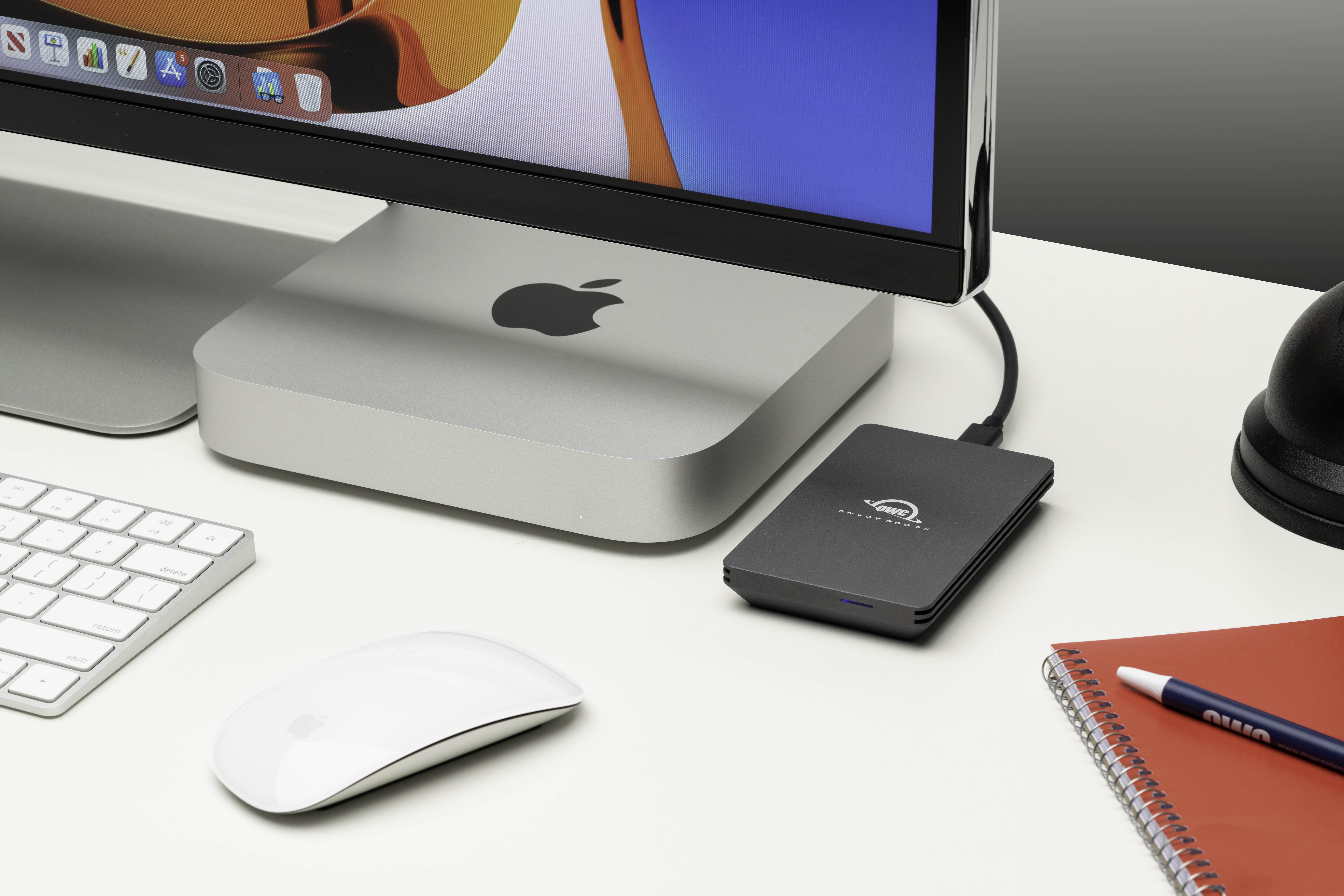 Konfiguracja biurka z Apple Mac Mini, klawiaturą, myszą i dyskiem twardym. Notatnik z długopisem.