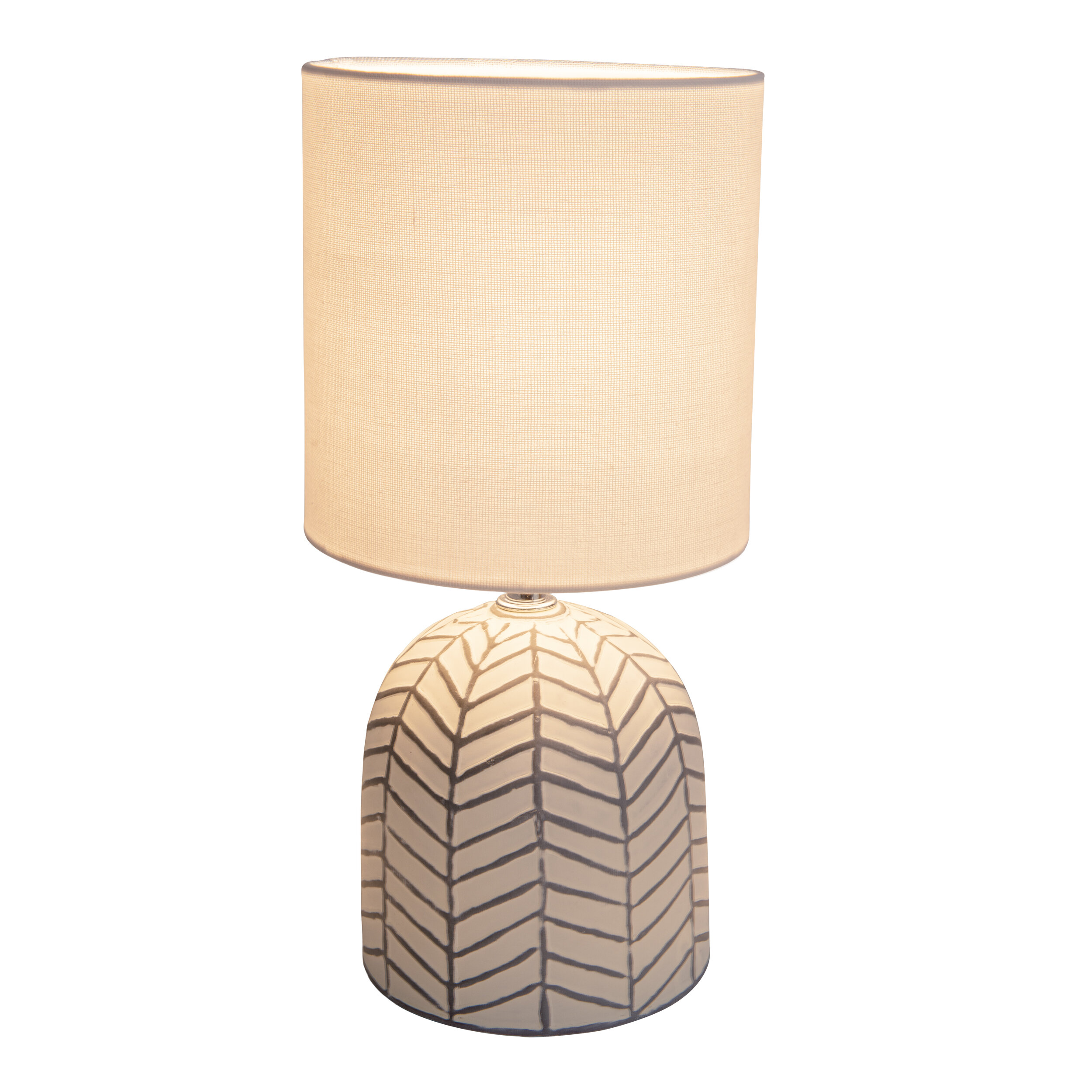 Tischlampe mit weißem Lampenschirm und gemustertem Sockel. Der Sockel hat ein graues Chevron-Design.