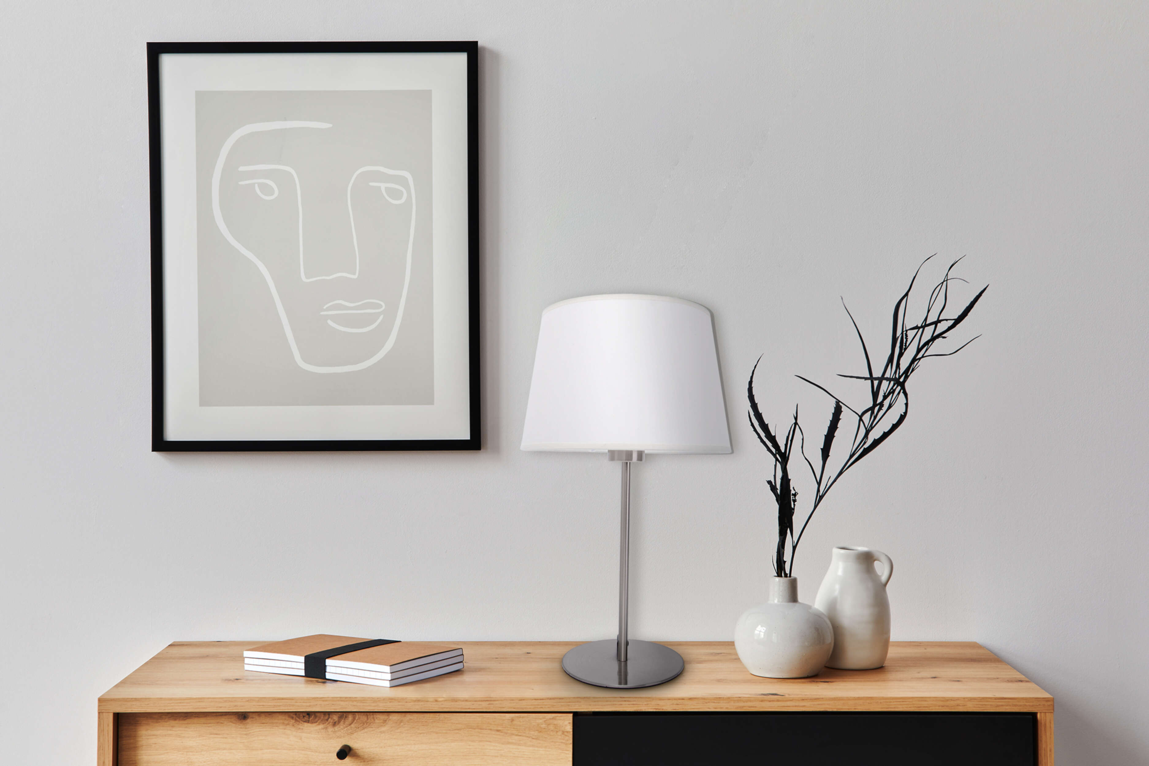 Eine Lampe auf einem Holztisch mit einer Zeichnung und Dekorationen an der Wand.