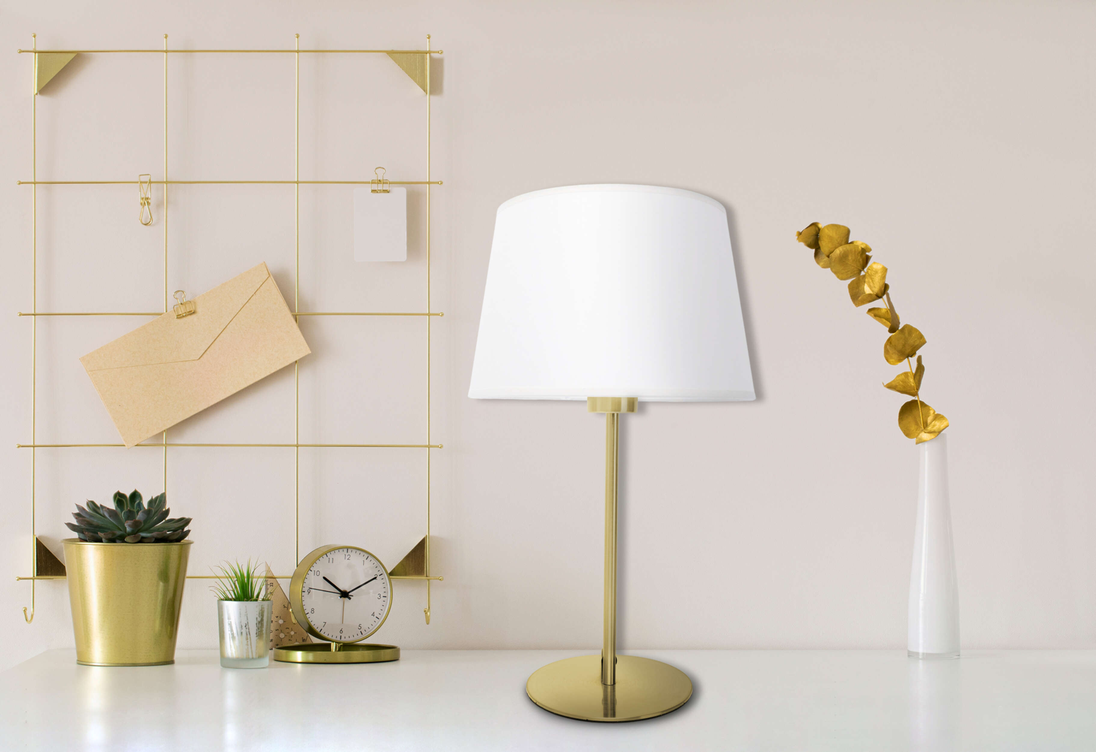 Schreibtisch mit Lampe, goldener Memotafel, Sukkulente, Uhr und Vase, auf beigem Hintergrund.