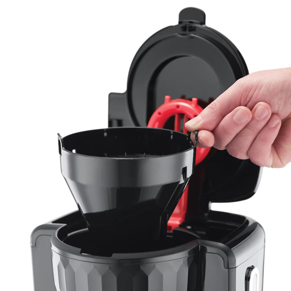 Mano de una persona colocando un filtro de café negro en una cafetera negra.