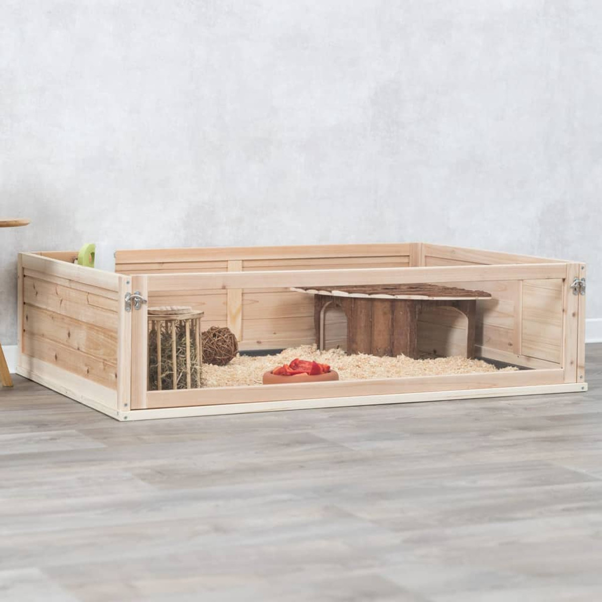 Holzgehege für Haustiere mit Einstreu, Haus und Futter-/Wassernäpfen.