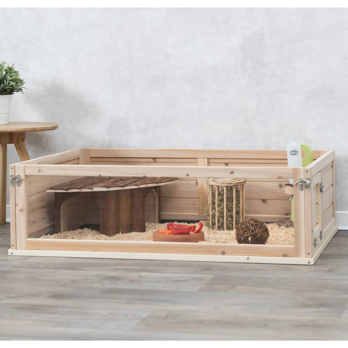 Recinto para perros de madera con accesorios dentro. Mesa de madera al fondo.